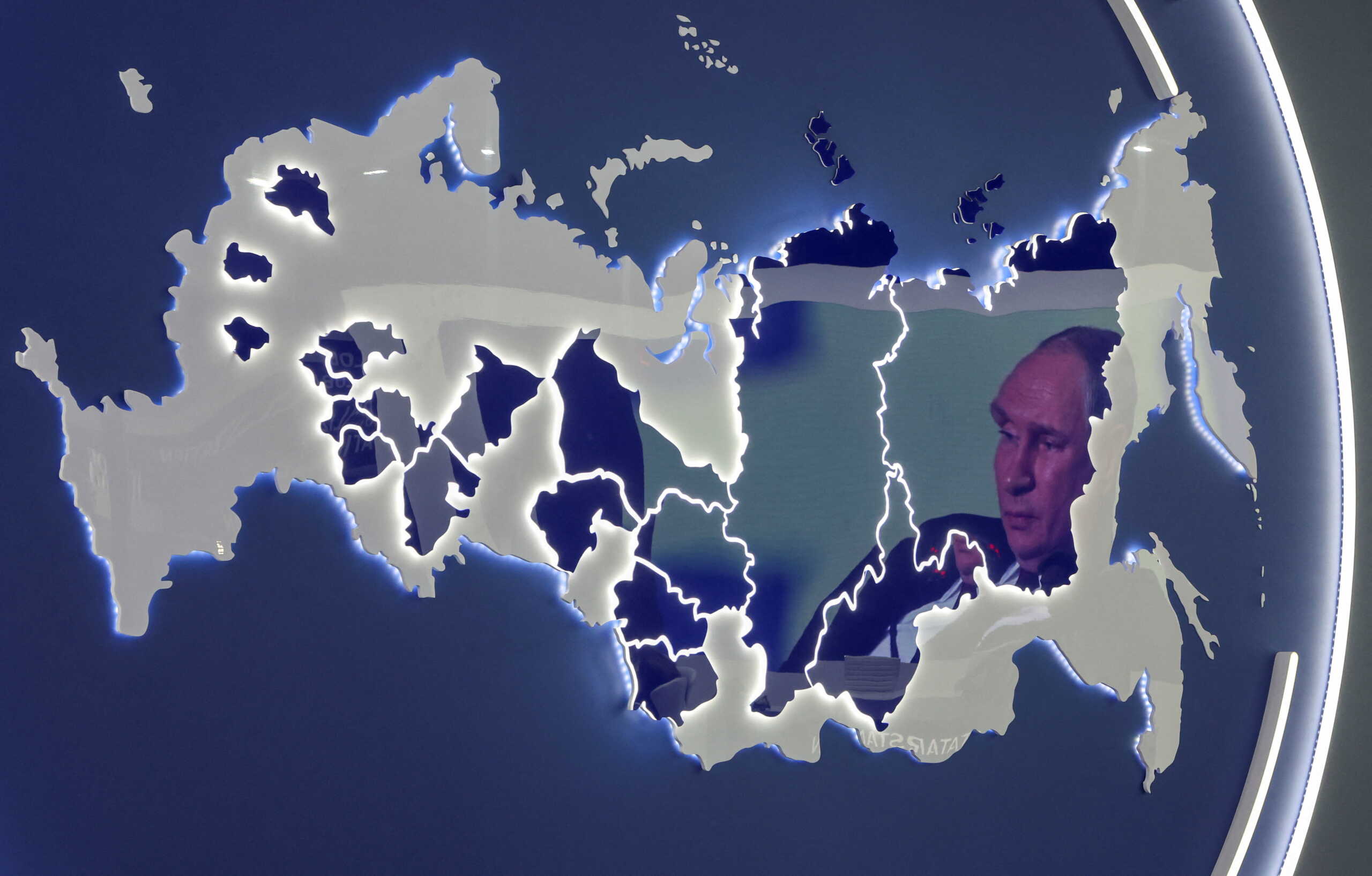 A screen showing Russian President Vladimir Putin is reflected in a stand displaying the map of Russia at the St. Petersburg International Economic Forum (SPIEF) in Saint Petersburg, Russia June 17, 2022. REUTERS
