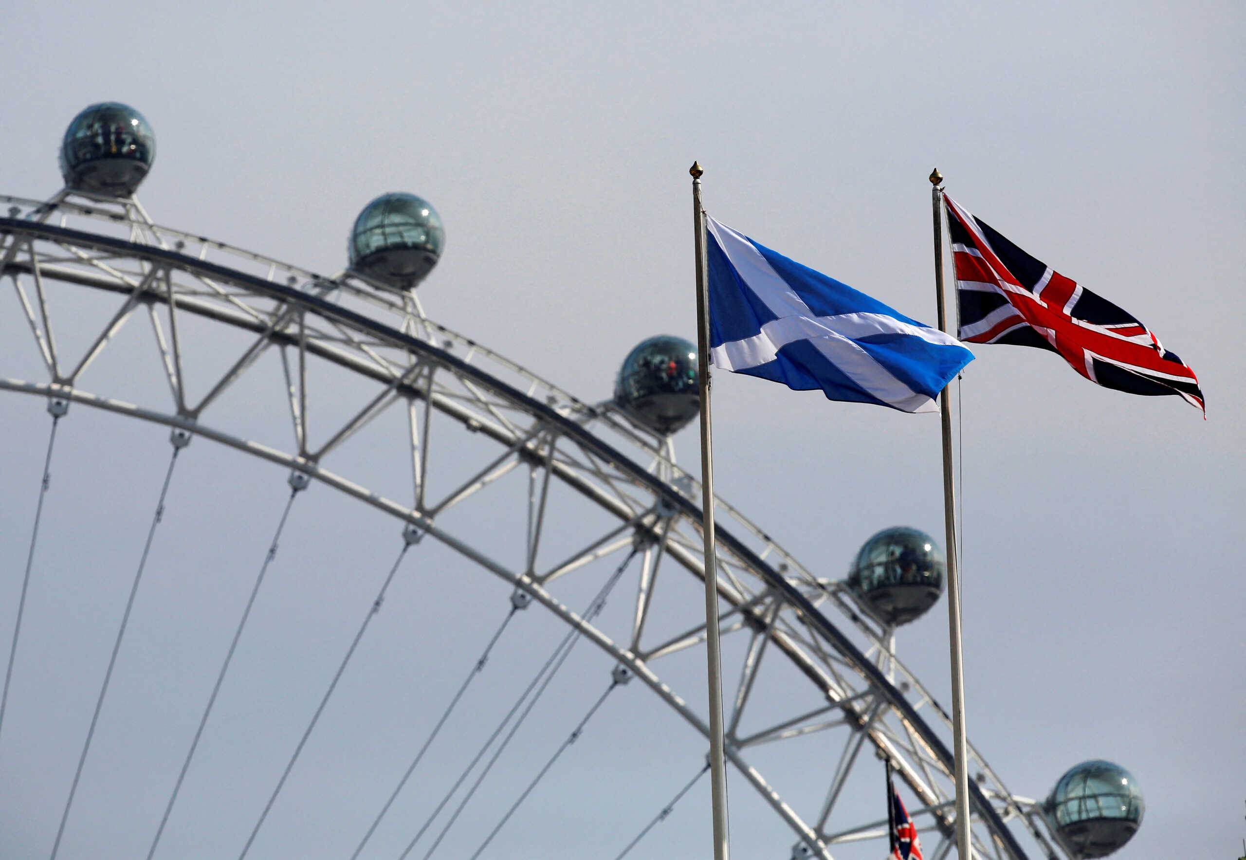 FILE PHOTO: A Scottish Saltire flag and British Union flag fly together with the London Eye behind in London September 19, 2014. Scotland spurned independence in a historic referendum that threatened to rip the United Kingdom apart, sow financial turmoil and diminish Britiain's remaining global clout.  REUTERS