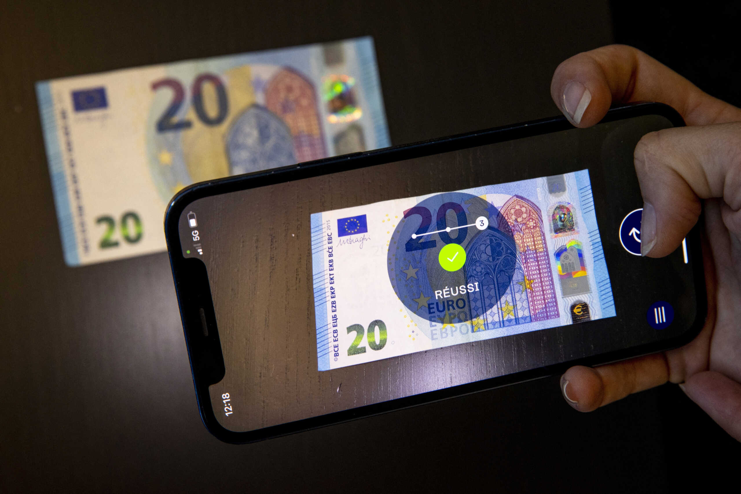 A staff uses an iPhone with the ValiCash application, made by Koenig & Bauer Banknote Solutions, to authenticate a Euro banknote during a media visit in Lausanne, Switzerland, June 23, 2022.  REUTERS