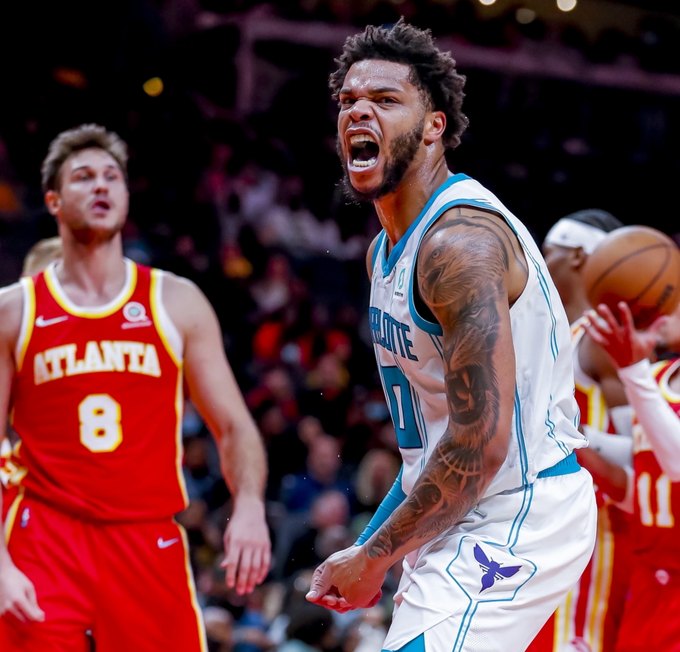 epa09595055 Charlotte Hornets forward Miles Bridges (R) reacts after dunking against Atlanta Hawks forward Danilo Gallinari (L) of Italy during the second half of the NBA basketball game between the Charlotte Hornets and the Atlanta Hawks at State Farm Arena in Atlanta, Georgia, USA, 20 November 2021.  EPA