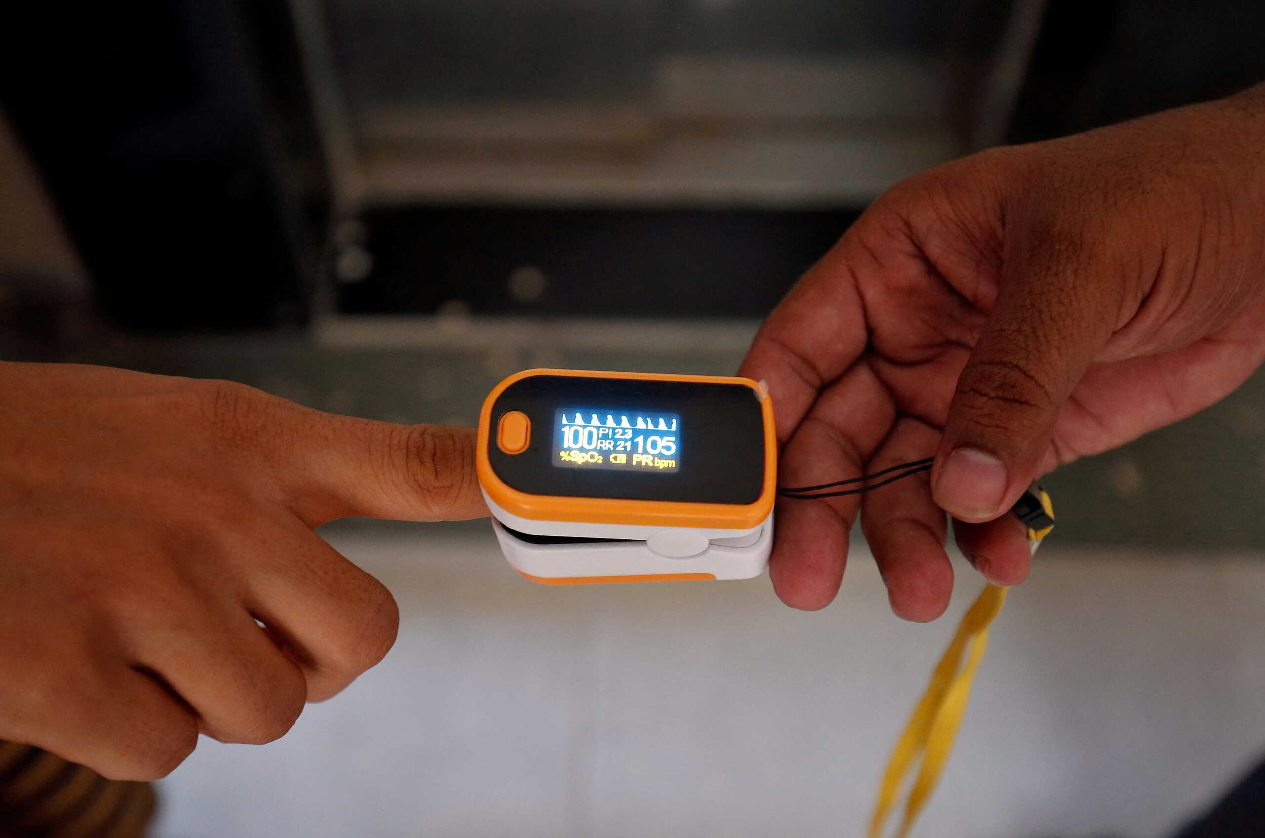 FILE PHOTO: A medical worker (R) puts a pulse oximeter on a woman's finger to check her oxygen level during a door-to-door survey for the coronavirus disease (COVID-19) amidst its spread in Ahmedabad, India June 26, 2020. REUTERS