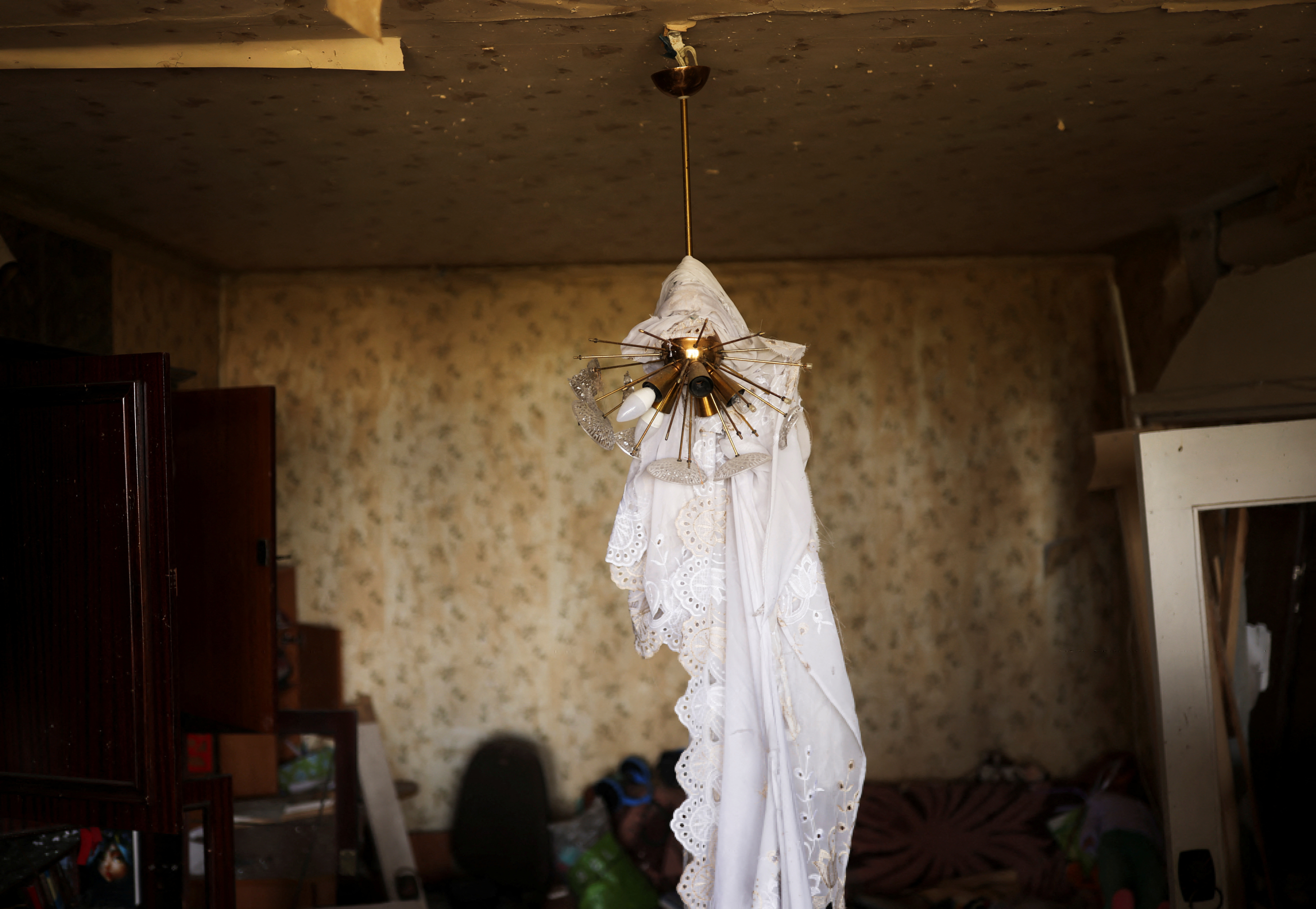 A curtain hangs on a lamp inside a flat after the building was damaged by a military strike, as Russia's invasion of Ukraine continues, in northern Saltivka, in Kharkiv, Ukraine July 13, 2022. REUTERS