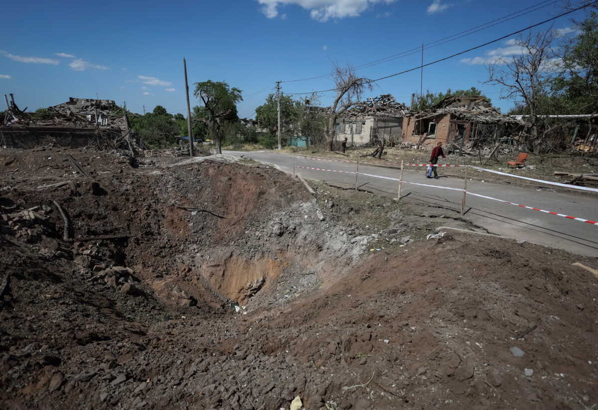 A shell crater is seen near buildings destroyed by Russian military strike, amid Russia's invasion on Ukraine, in the town of Druzhkivka, in Donetsk region, Ukraine June 6, 2022. REUTERS