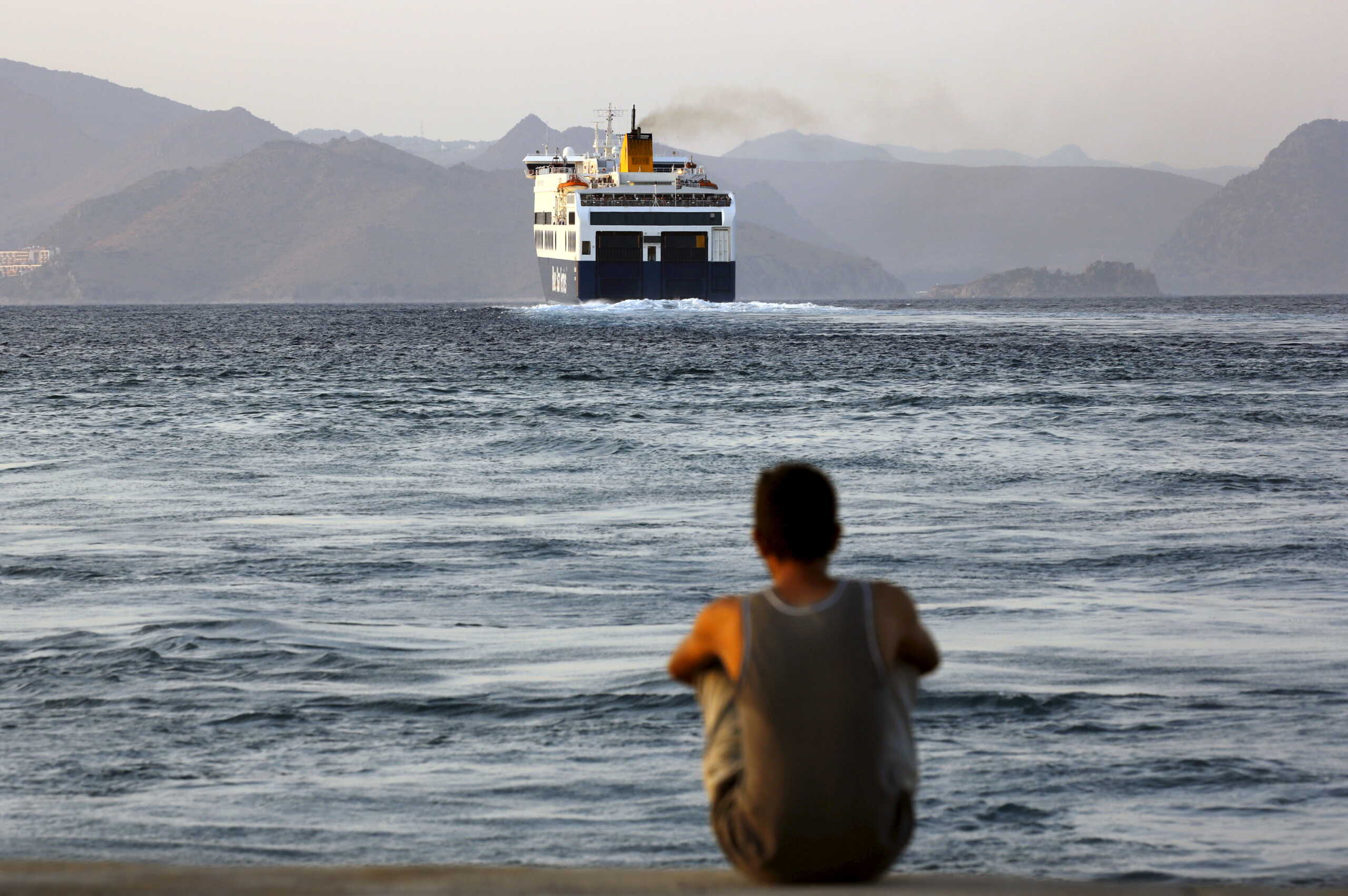 A Bangladeshi migrant, pending temporary documentation, watches from the port of Kos, Greece, a ferry bound for the port of Piraeus near Athens August 10, 2015. Thousands of refugees and migrants are stranded on Greek islands -- in some cases for over two weeks -- waiting for temporary documents before continuing their travel to northern Europe. The United Nations refugee agency (UNHCR) called on Greece to take control of the "total chaos" on Mediterranean islands, where thousands of migrants have landed. About 124,000 have arrived this year by sea, many via Turkey, according to Vincent Cochetel, UNHCR director for Europe. REUTERS