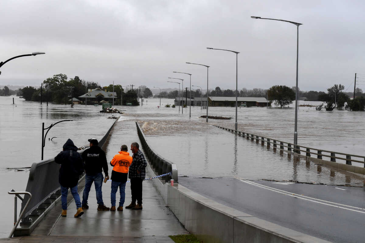 People look on as the Windsor Bridge is submerged under floodwater from the swollen Hawkesbury River in Windsor, north west of Sydney, Australia, July 4, 2022.  AAP Image