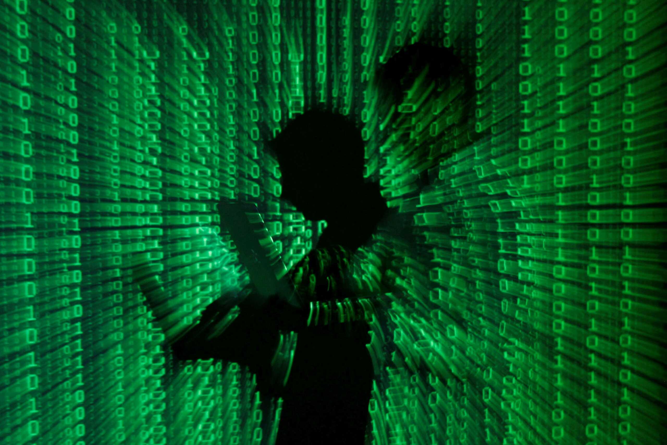 FILE PHOTO: An illustration picture shows a projection of binary code on a man holding a laptop computer, in an office in Warsaw June 24, 2013. REUTERS