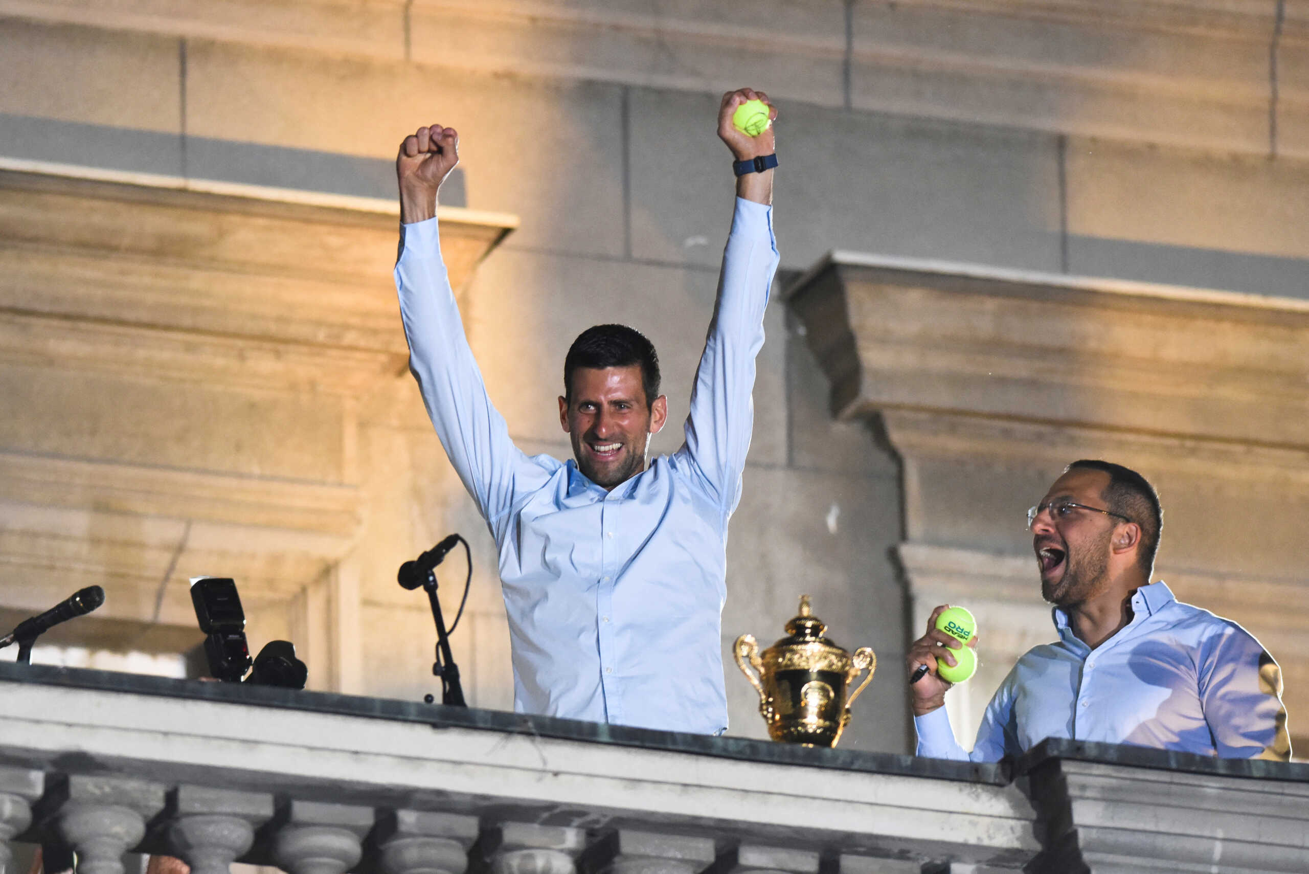 Serbian tennis player Novak Djokovic holds a tennis ball and waves to fans during a welcoming ceremony in front of the city hall, after he won his seventh Wimbledon title, in Belgrade, in Serbia, July 11, 2022. REUTERS