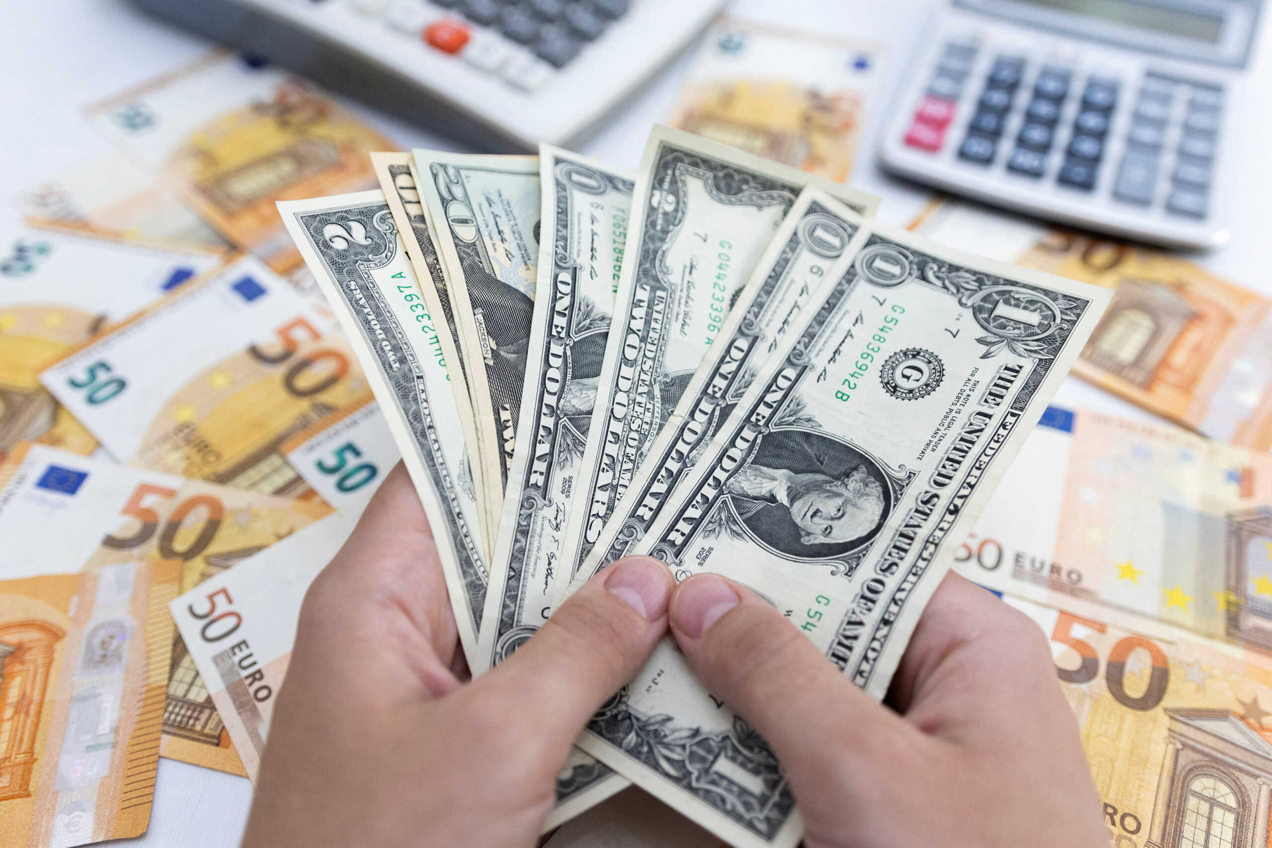 FILE PHOTO: Woman holds U.S. dollar banknotes in front of Euro banknotes in this illustration taken May 30, 2022. REUTERS