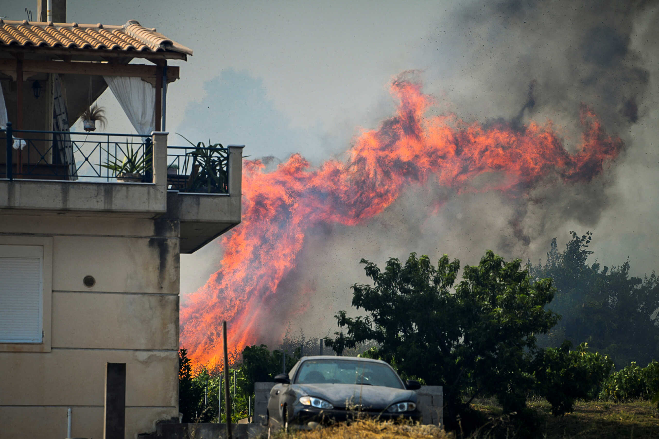 Flames rise near a house, as a wildfire burns at the village of Krestena, in the western Peloponnese, Greece July 24, 2022. Giannis Spirounis