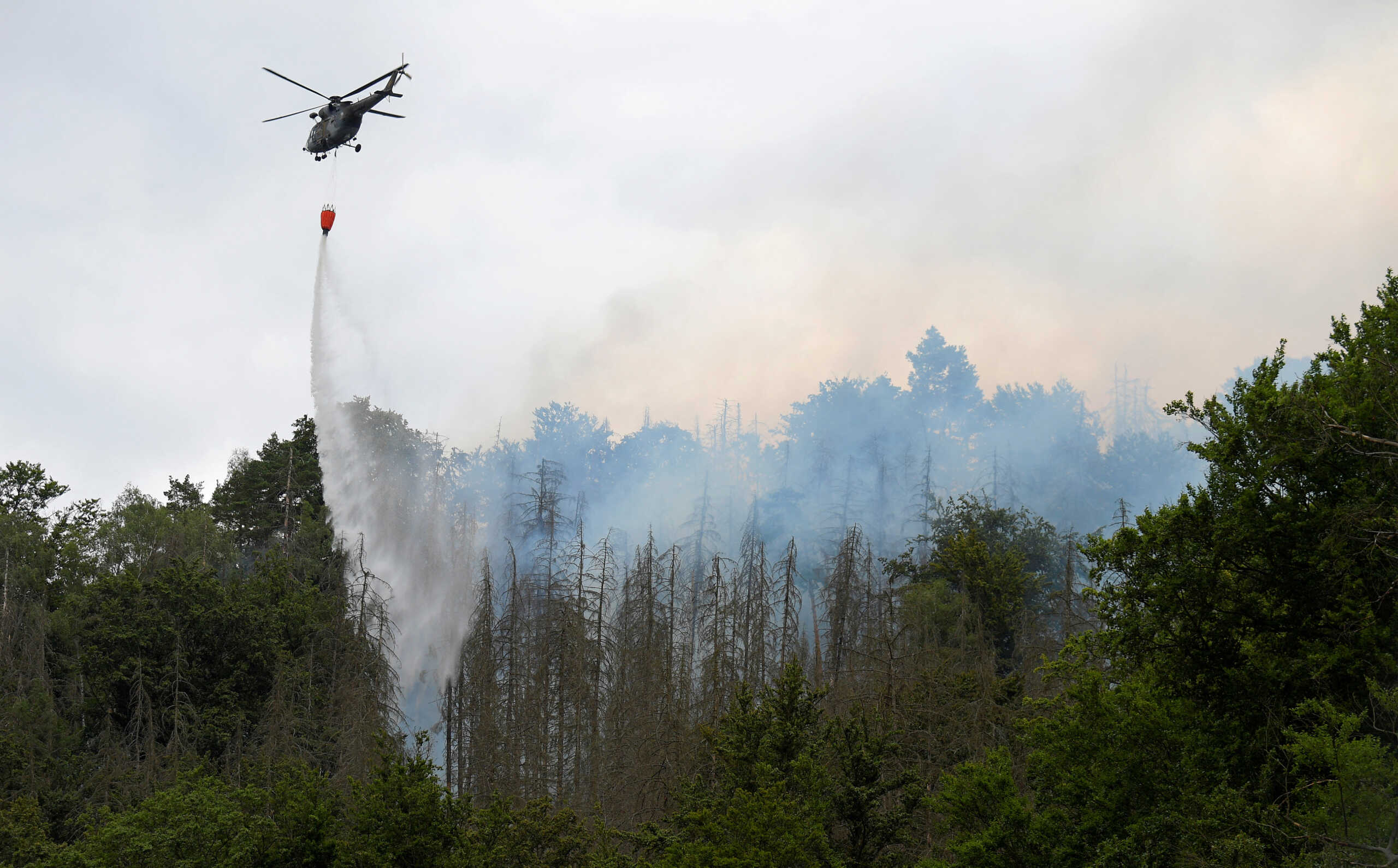 A Czech army helicopter helps to extinguish a forest fire during a heatwave close to the German-Czech border near Hrenso, Czech Republic, July 26, 2022. REUTERS