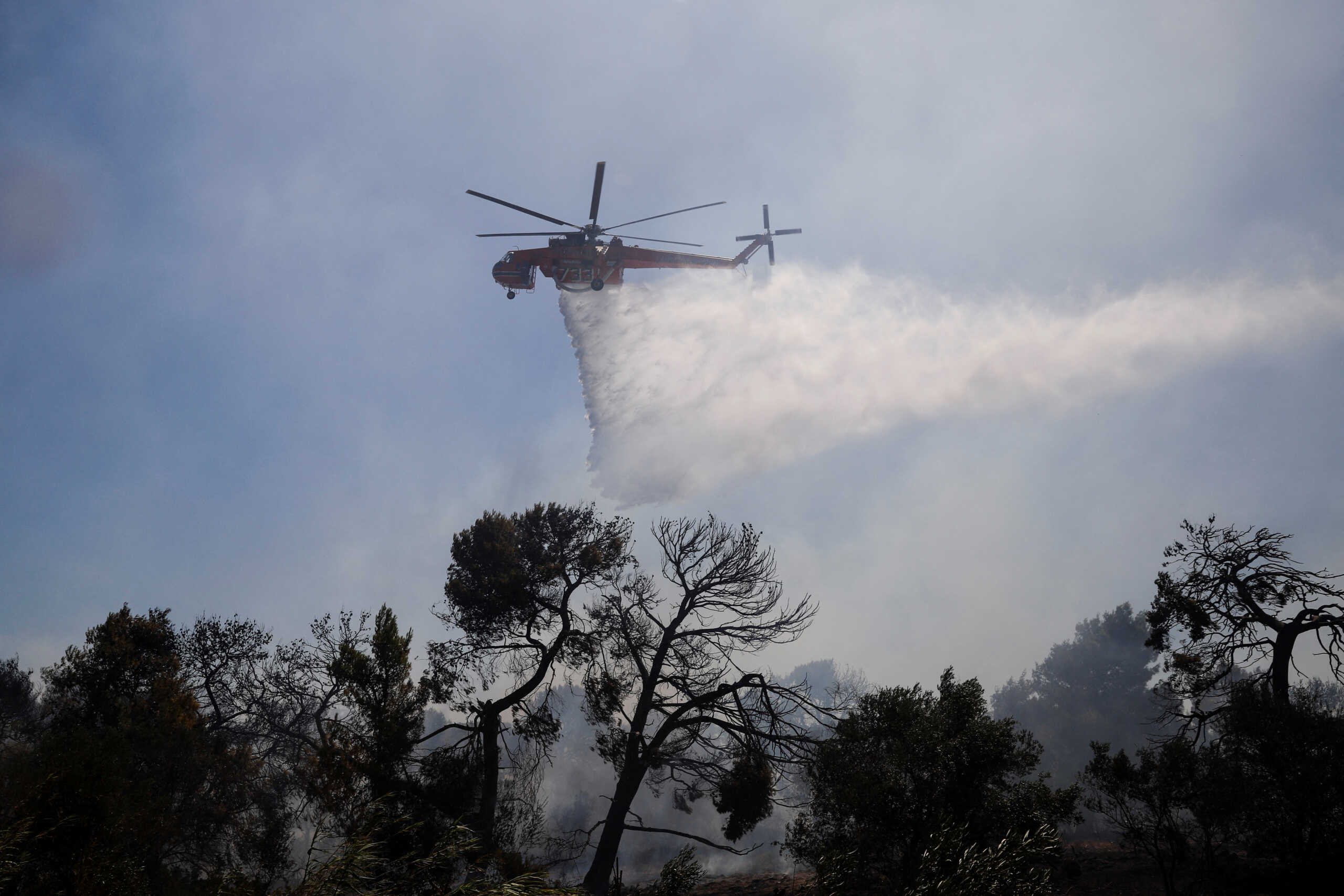 A firefighting helicopter makes a water drop as a wildfire burns in Pallini, near Athens, Greece July 20, 2022. REUTERS