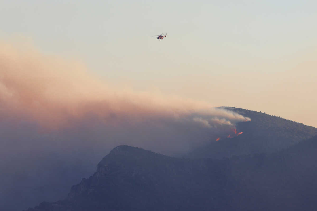 A firefighting helicopter flies over a wildfire raging on the island of Samos, Greece, July 13, 2022. REUTERS
