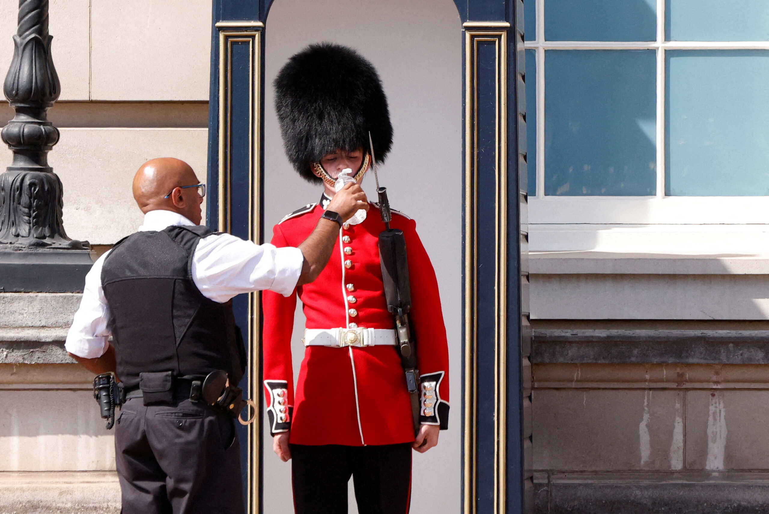 A member of the Queen's Guard receives water to drink during the hot weather, outside Buckingham Palace in London, Britain, July 18, 2022. REUTERS