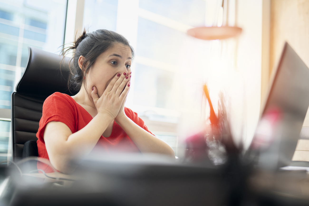 Shocked young woman looking at laptop screen