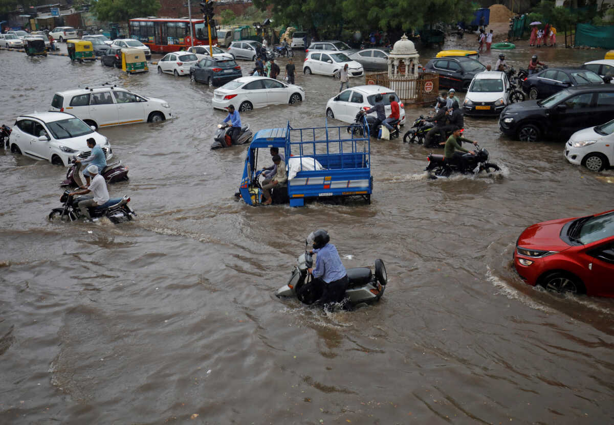 People move their vehicles through water-logged roads after heavy rains in Ahmedabad, India, July 8, 2022. REUTERS