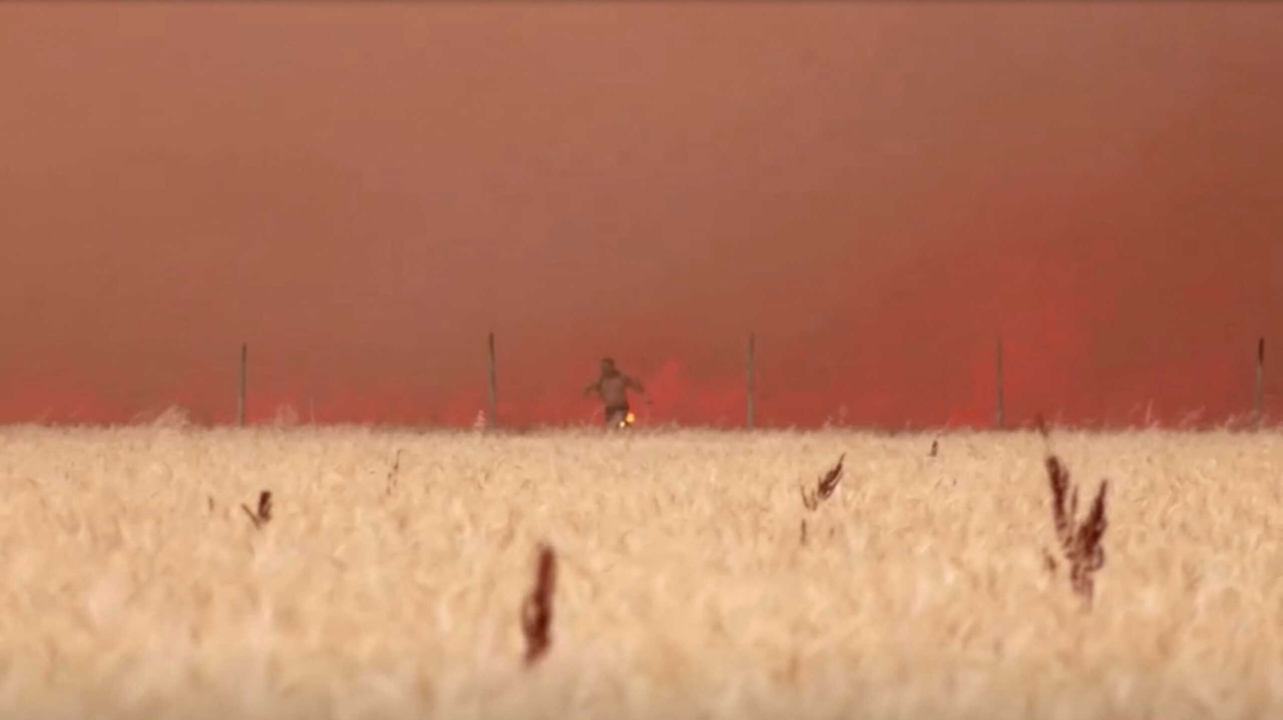 A man emerges from flames with burning clothes, as a wildfire burns in Tabara, Zamora Province, Spain, July 18, 2022 in this screen grab taken from a video. REUTERS