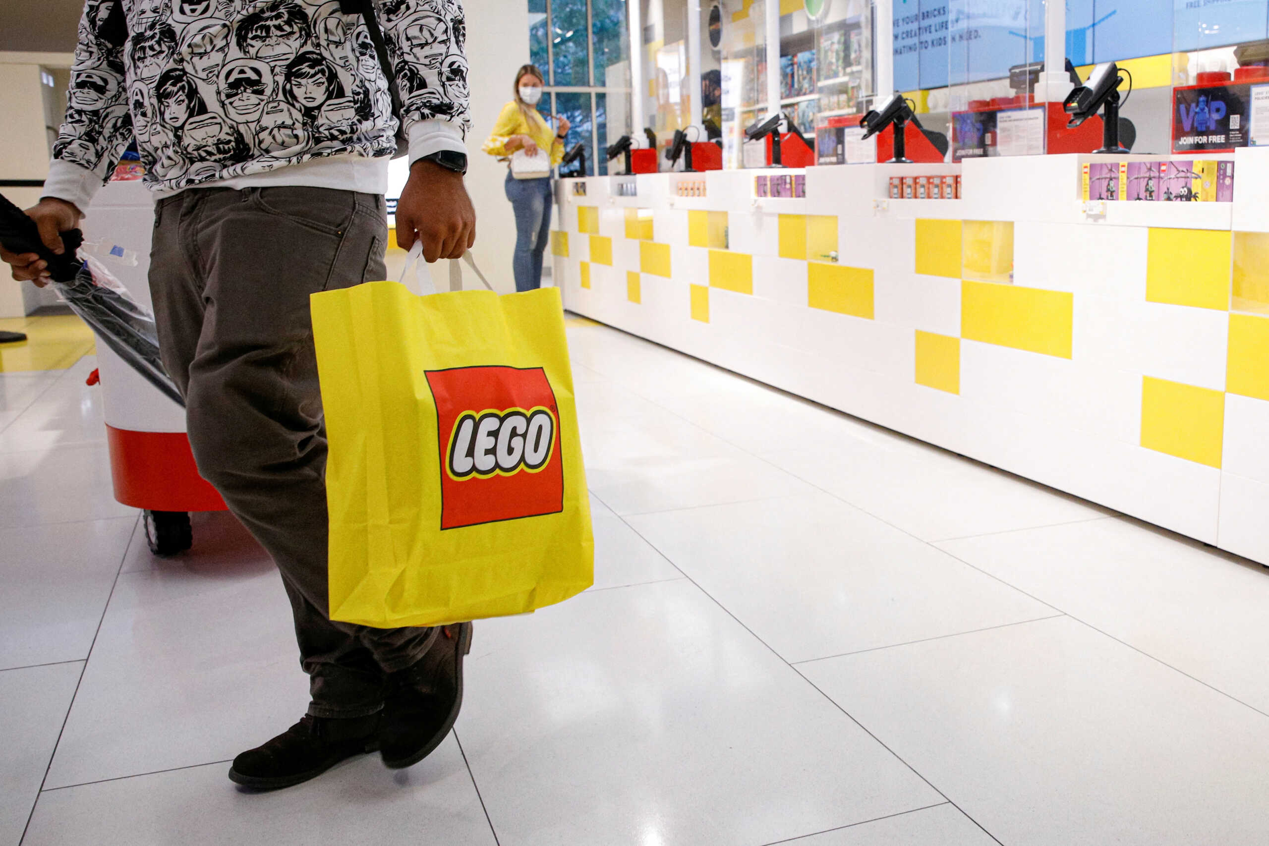 FILE PHOTO: A customer carries a bag while shopping in the 5th Avenue Lego store in New York City, U.S., September 28, 2021.  REUTERS