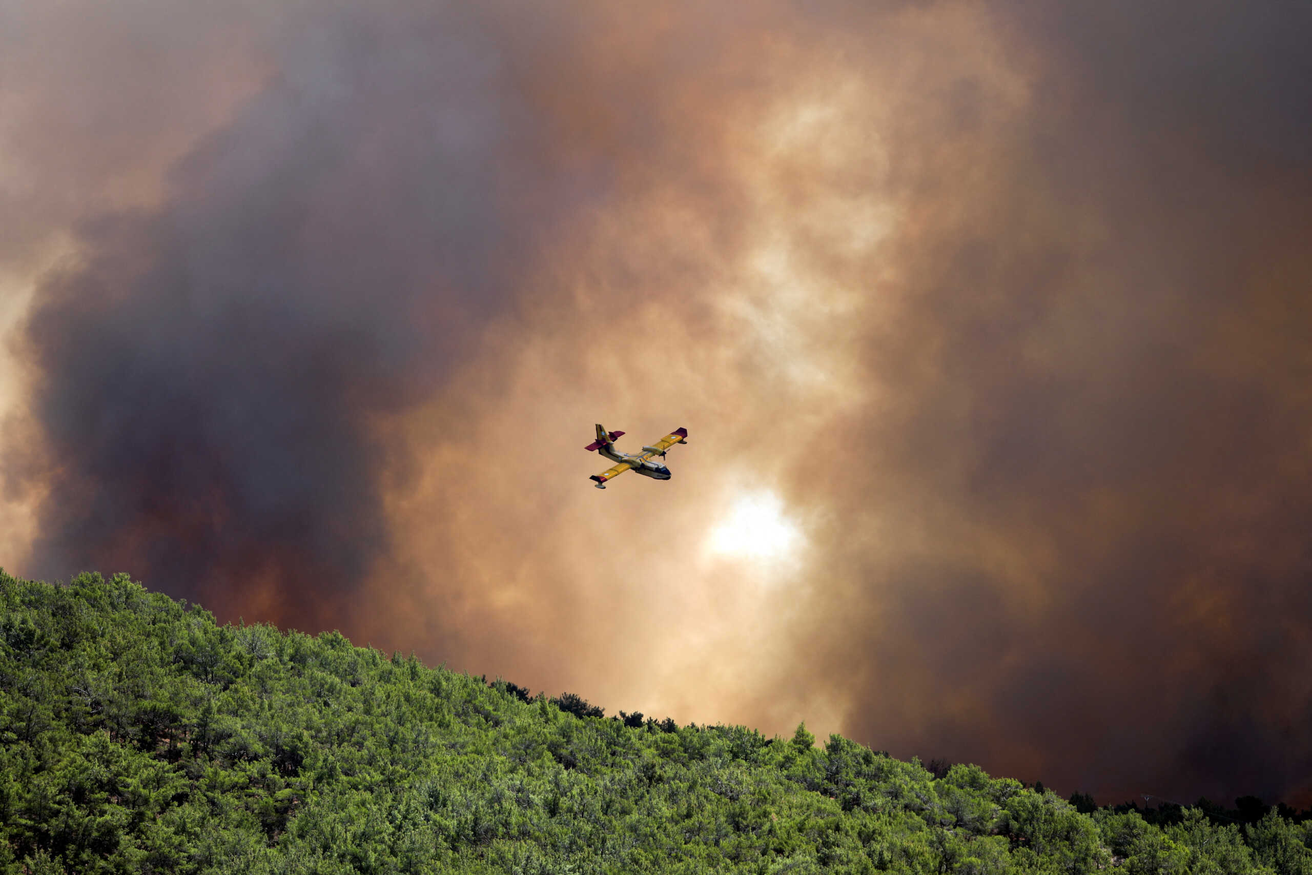 A firefighting plane flies over wildfire burning near the village of Vatera, on the island of Lesbos, Greece July 23, 2022. REUTERS