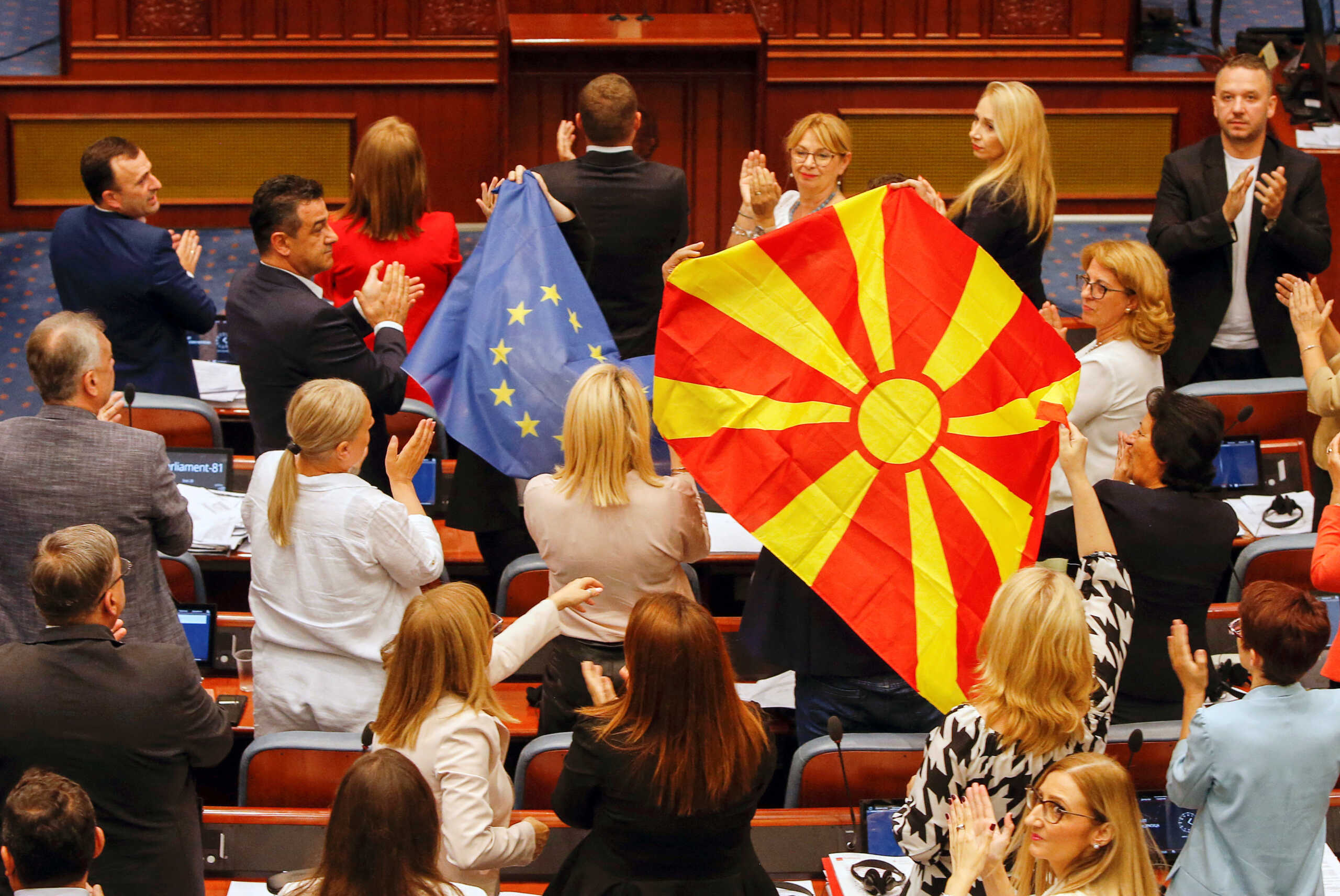 North Macedonian members of Parliament from the ruling SDSM party, hold European Union and North Macedonian flags, during a parliamentary debate on a French-brokered deal aimed at settling disputes with Bulgaria and clearing the way to EU membership, in Skopje, North Macedonia, July 16, 2022. REUTERS