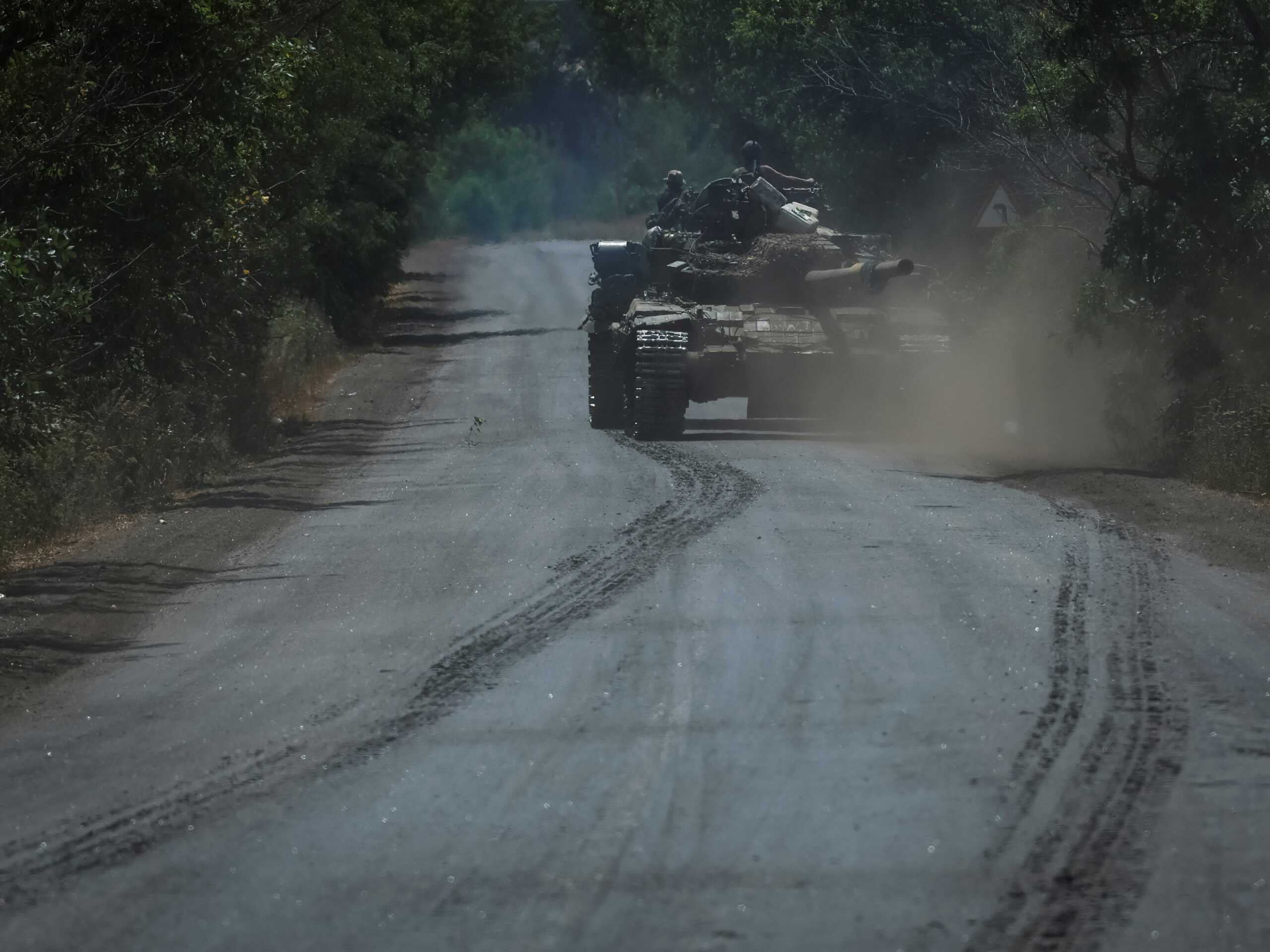 Ukrainian servicemen ride on a military vehicle as they tow a disabled tank, amid Russia's attack on Ukraine, in Donetsk region, Ukraine July 8, 2022. REUTERS