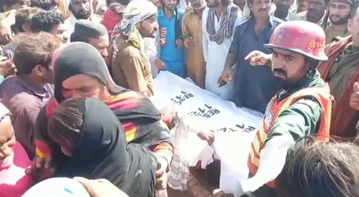Locals carry a dead body covered in a white sheet, after a boat carrying around 100 people capsized in a central Pakistani river, in Sadiqabad, Pakistan, July 18, 2022, in this still image taken from a handout video. Punjab Government