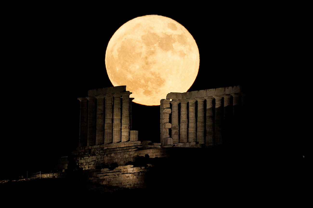 A full moon known as the "Strawberry Moon" rises behind the Temple of Poseidon, in Cape Sounion, near Athens, Greece, June 14, 2022. REUTERS