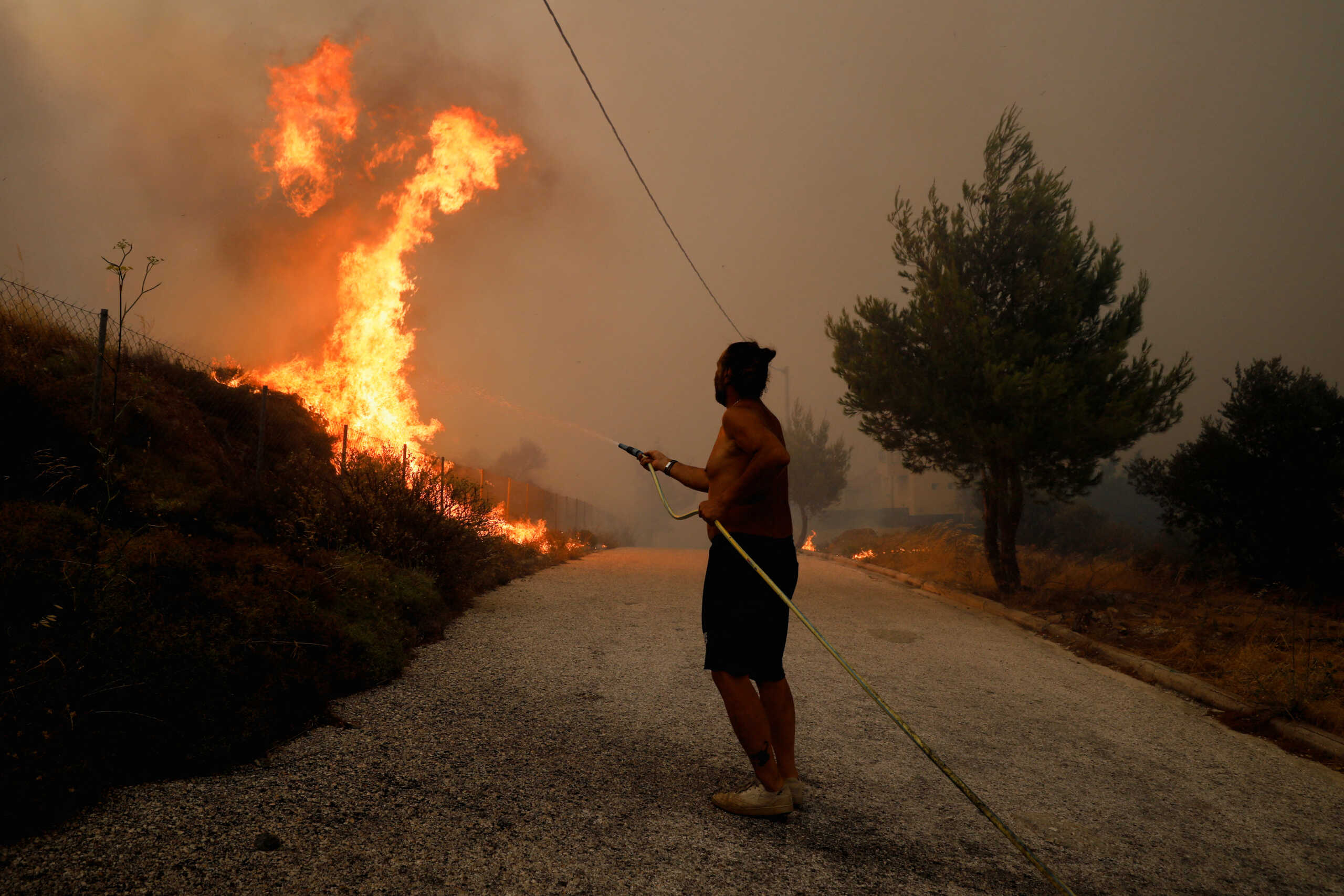 A resident tries to extinguish a wildfire in Ntrafi, Athens, Greece, July 19, 2022. REUTERS
