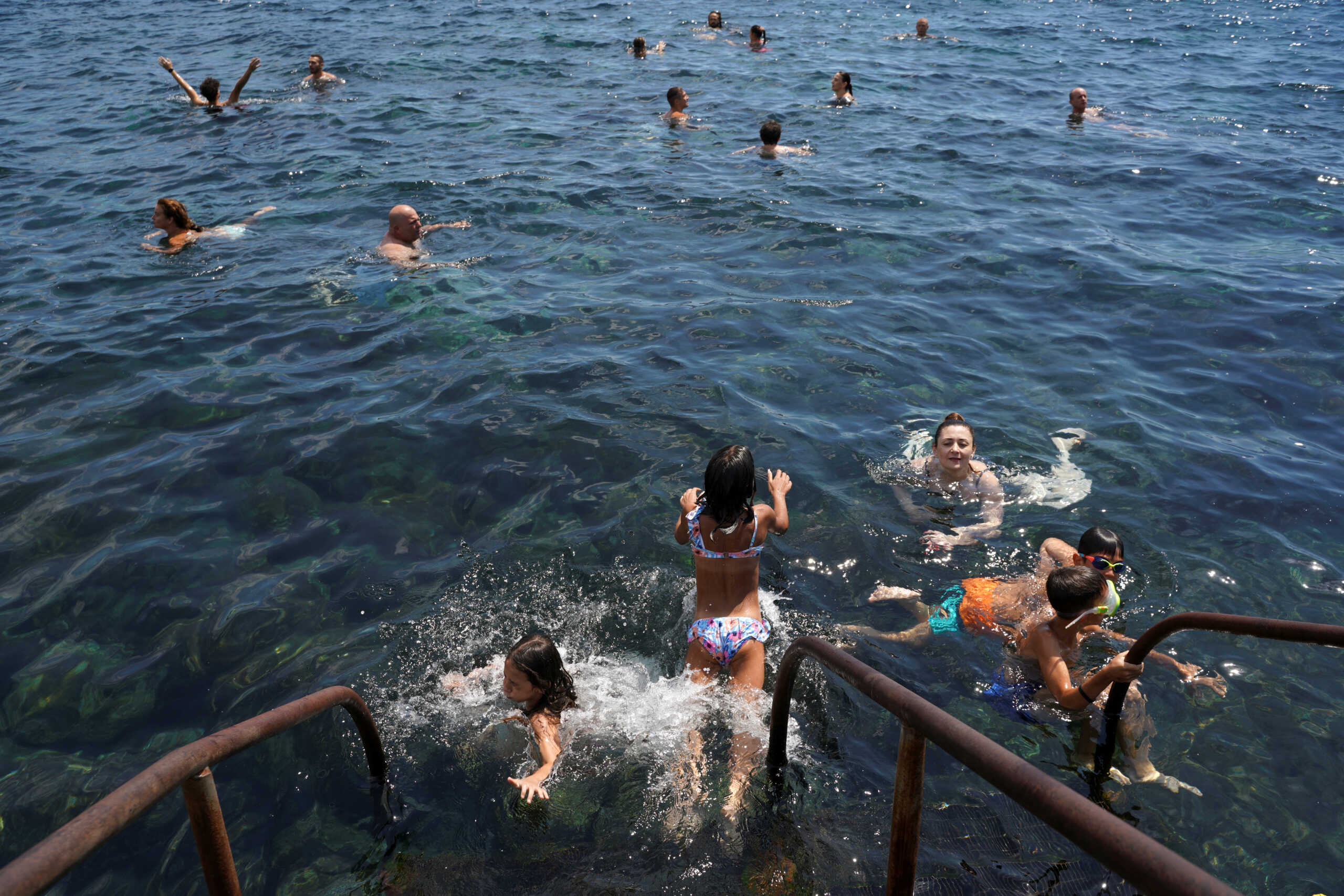 People take a bath in the sea, during the second heatwave of the summer, in Catania, Italy, July 14, 2022. REUTERS