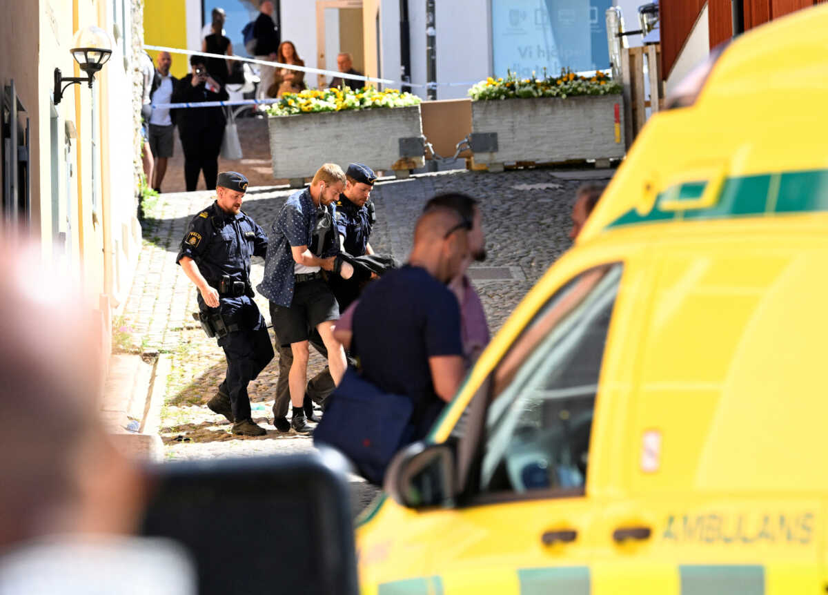 Police officers escort the apprehended male suspect after a woman was seriously injured in a stabbing at the Almedalen political festival at Visby, on Gotland island, Sweden July 6, 2022. TT News Agency
