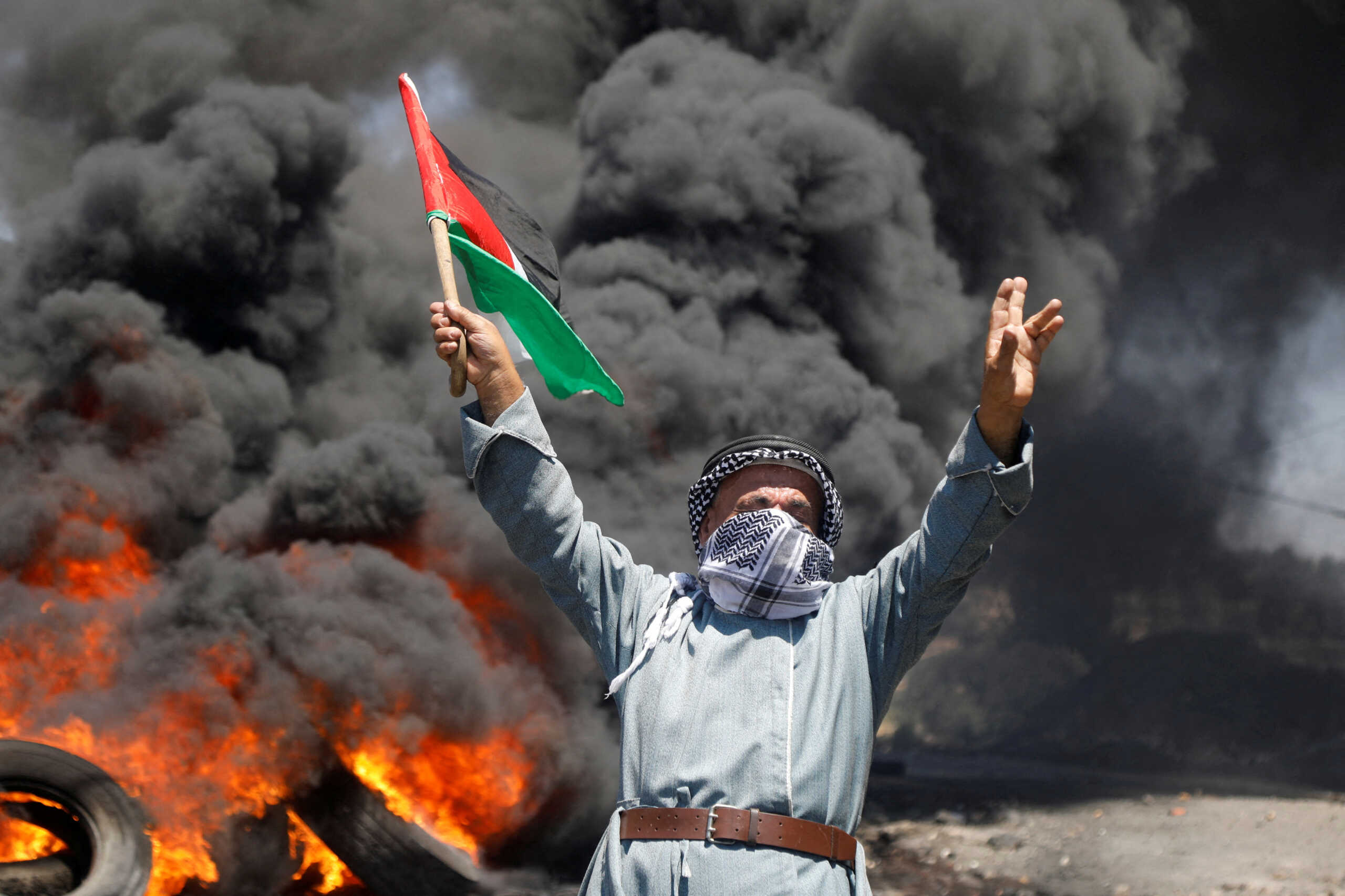 A man holds a Palestinian flag during a protest against Israeli settlement activity in Kafr Qaddum in the Israeli-occupied West Bank July 1, 2022. REUTERS