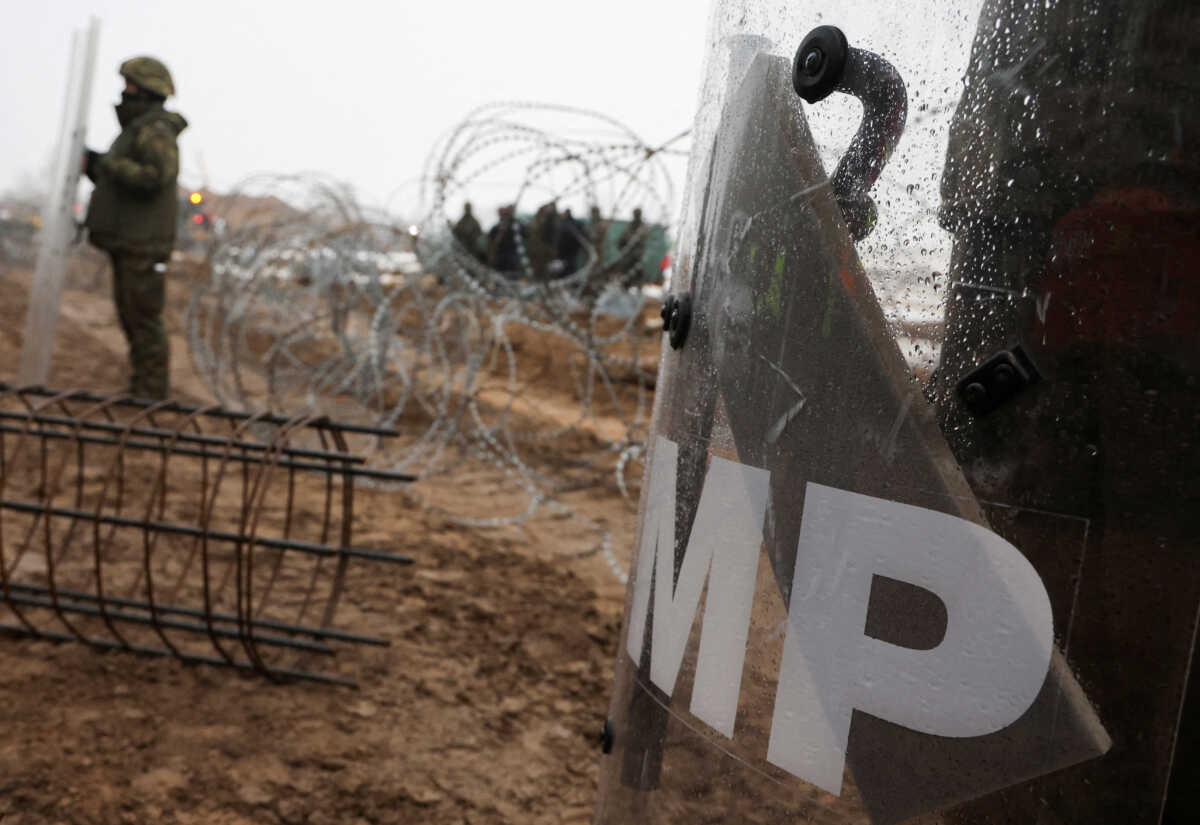 FILE PHOTO: Military Police soldiers keep watch as workers from Unibed company work at the construction site of a barrier at the border between Poland and Belarus, in Tolcze near Kuznica, Poland January 27, 2022. REUTERS