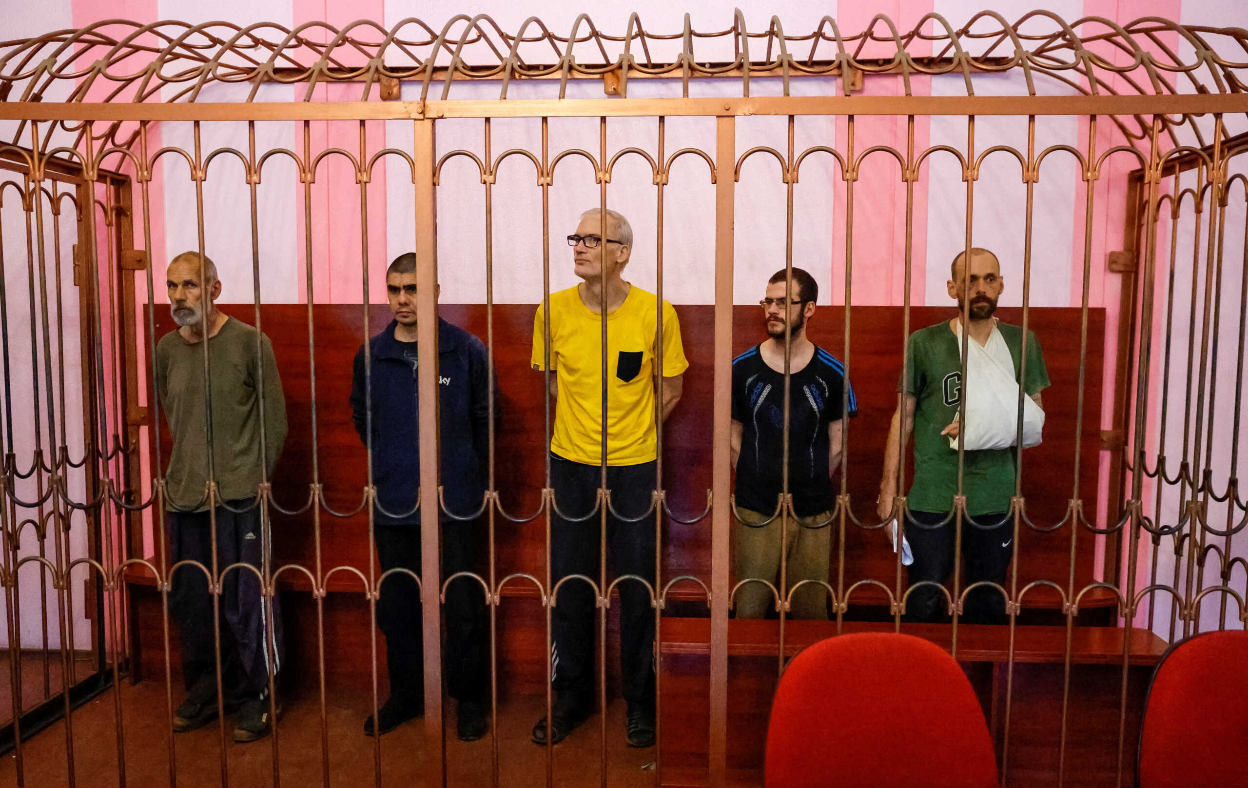 Foreign nationals Vjekoslav Prebeg from Croatia, Dylan Healy from Britain, John Harding from Britain, Mathias Gustafsson from Sweden and Andrew Hill from Britain, who were captured by pro-Russian forces while allegedly fighting for Ukrainian troops during Ukraine-Russia conflict, stand inside a defendants' cage during a court hearing in Donetsk, Ukraine August 15, 2022. REUTERS