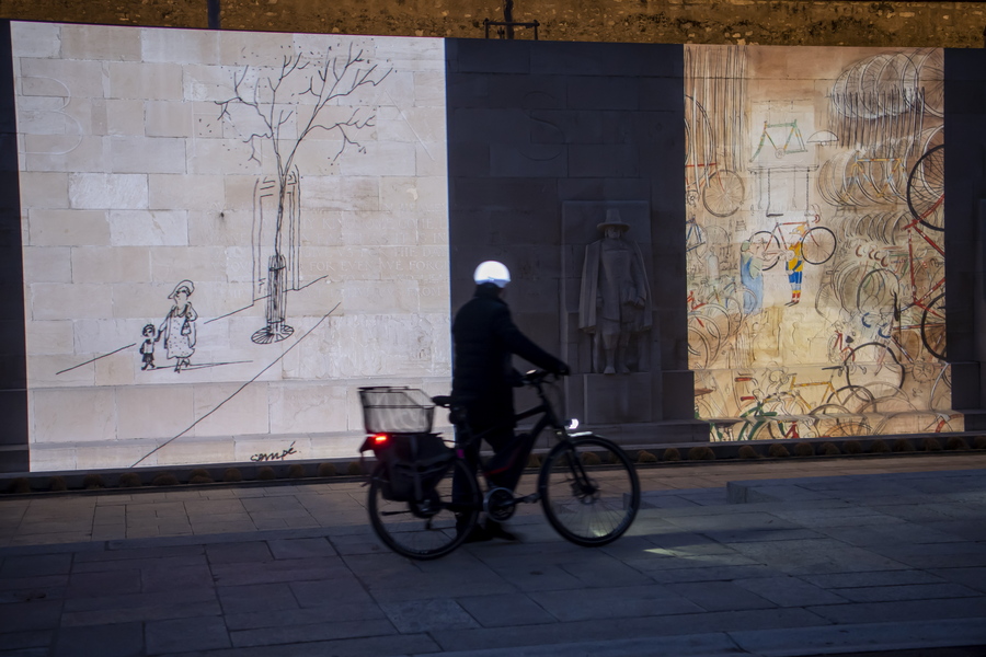epa09080688 A person looks at drawings by French cartoonist Jean-Jacques Sempe, known as Sempe, as part of a series of nighttime screenings with the theme 'A Springtime with Sempe' at the Parc des Bastions in Geneva, Switzerland, 17 March 2021, as an initiative of the 'societe de lecture'.  EPA