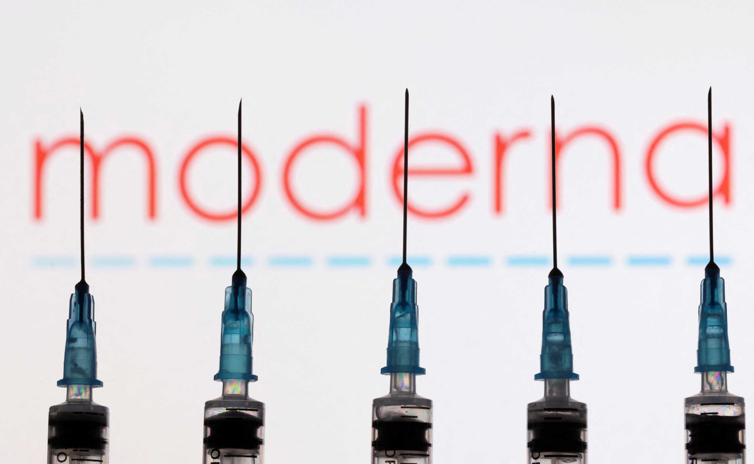 FILE PHOTO: Syringes with needles are seen in front of a displayed Moderna logo in this illustration taken November 27, 2021. REUTERS