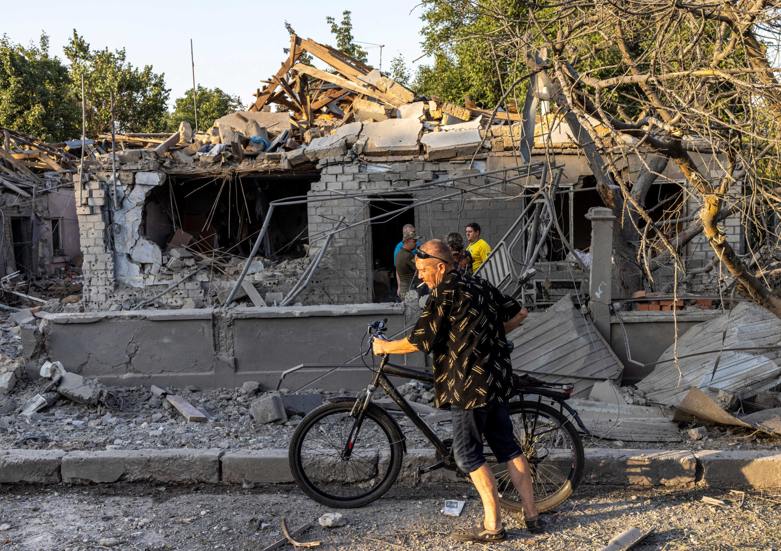 A man walks with his bicycle past houses destroyed by a strike, amid Russia's invasion, in Mykolaiv, Ukraine, August 29, 2022. REUTERS