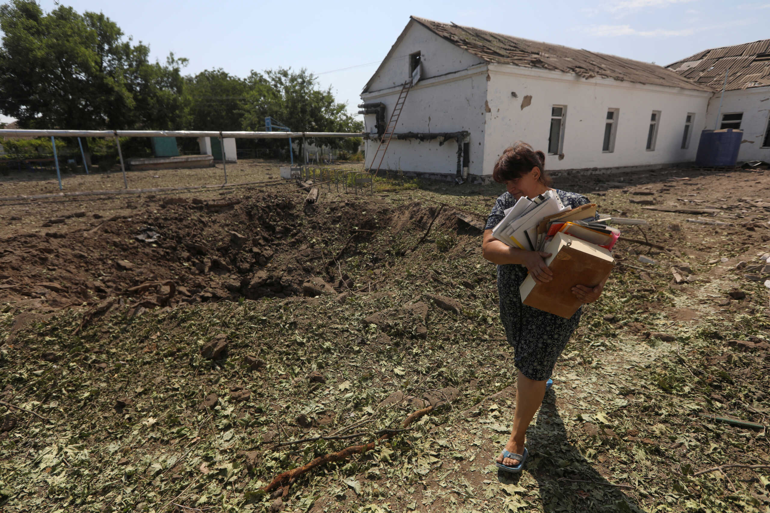 An employee carries out documents from a school building damaged by a Russian missile strike, as Russia's attack on Ukraine continues, in Mykolaiv, Ukraine July 28, 2022.  REUTERS