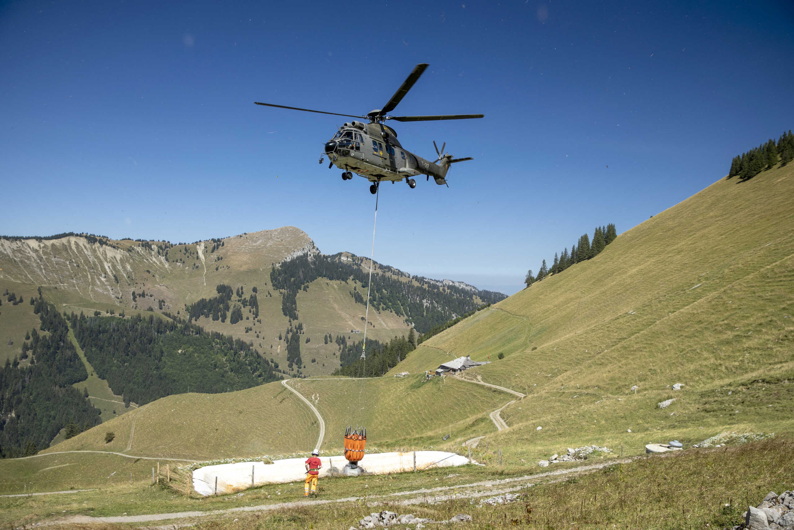 A Swiss Air Force Super Puma helicopter delivers water for cows in the Tissiniva mountain pasture due to an ongoing drought in Charmey, Switzerland, August 10, 2022.  REUTERS