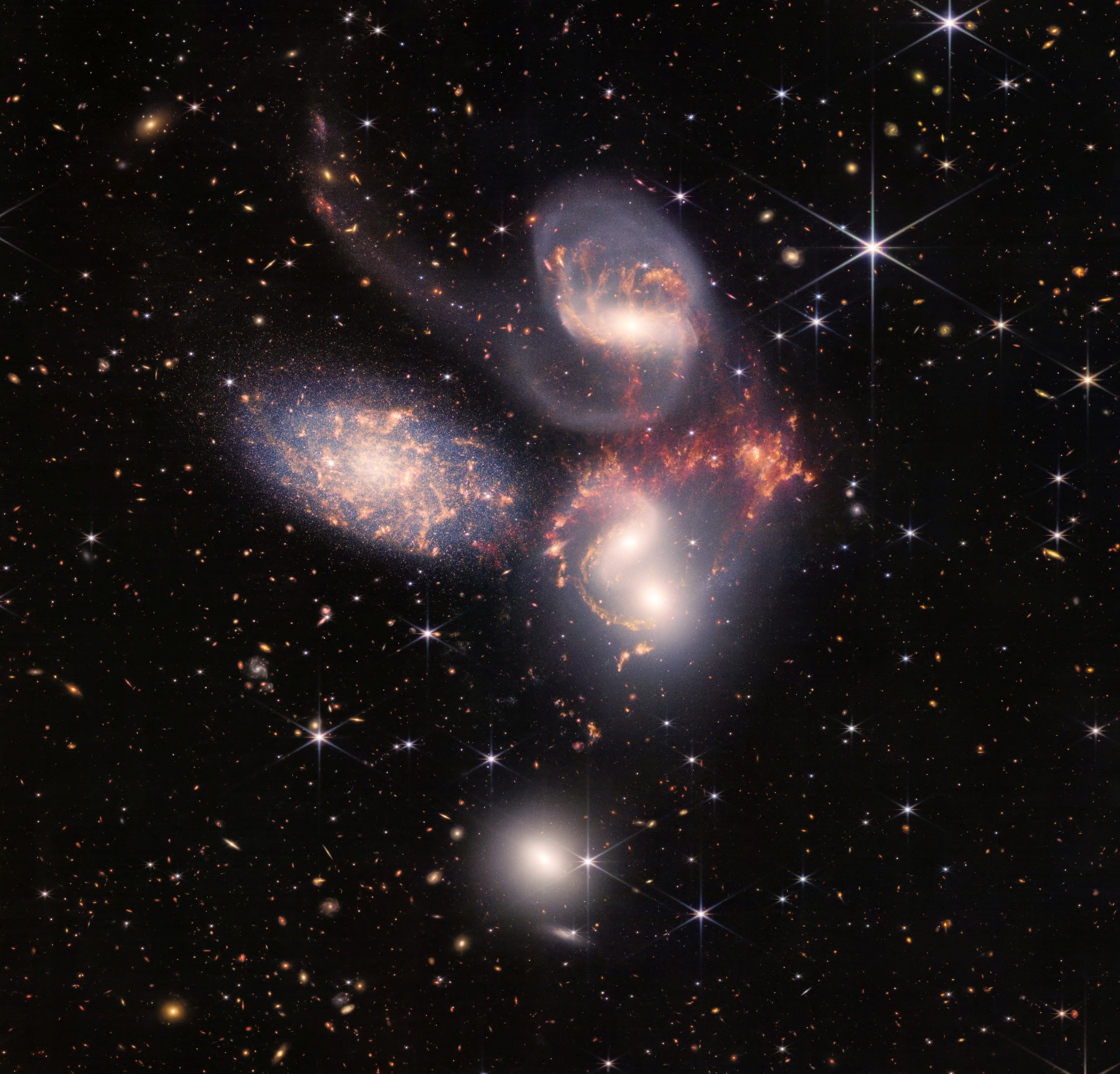 A group of five galaxies that appear close to each other in the sky: two in the middle, one toward the top, one to the upper left, and one toward the bottom are seen in a mosaic or composite of near and mid-infrared data from NASA's James Webb Space Telescope, a revolutionary apparatus designed to peer through the cosmos to the dawn of the universe and released July 12, 2022.    NASA, ESA, CSA, STScI, Webb ERO Production Team