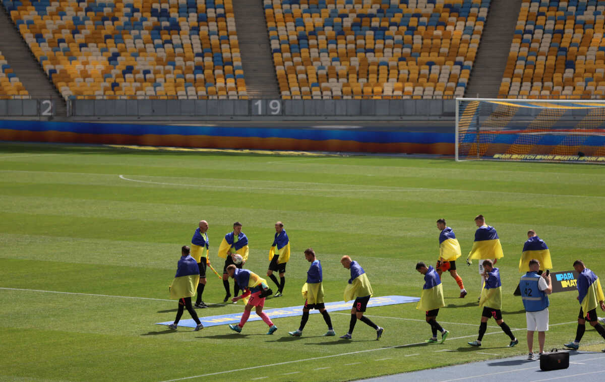 Soccer Football - Ukrainian Premier League - Shakhtar Donetsk v FC Metalist 1925 Kharkiv - NSC Olympiyskiy, Kyiv, Ukraine - August 23, 2022 Players and officials draped with Ukrainian flags walk out onto the pitch before the match as Russia's attack on Ukraine continues REUTERS