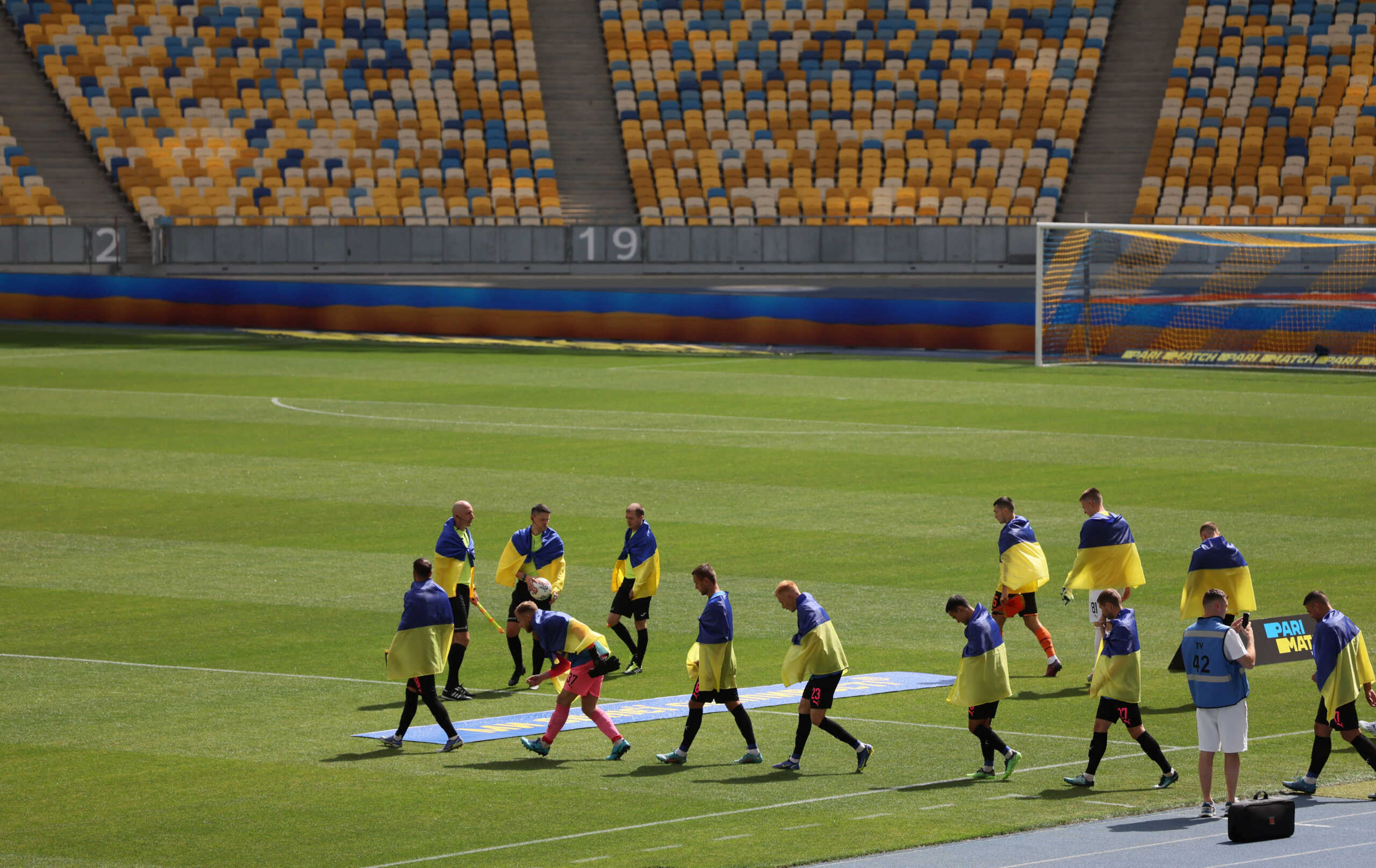 Soccer Football - Ukrainian Premier League - Shakhtar Donetsk v FC Metalist 1925 Kharkiv - NSC Olympiyskiy, Kyiv, Ukraine - August 23, 2022 Players and officials draped with Ukrainian flags walk out onto the pitch before the match as Russia's attack on Ukraine continues REUTERS