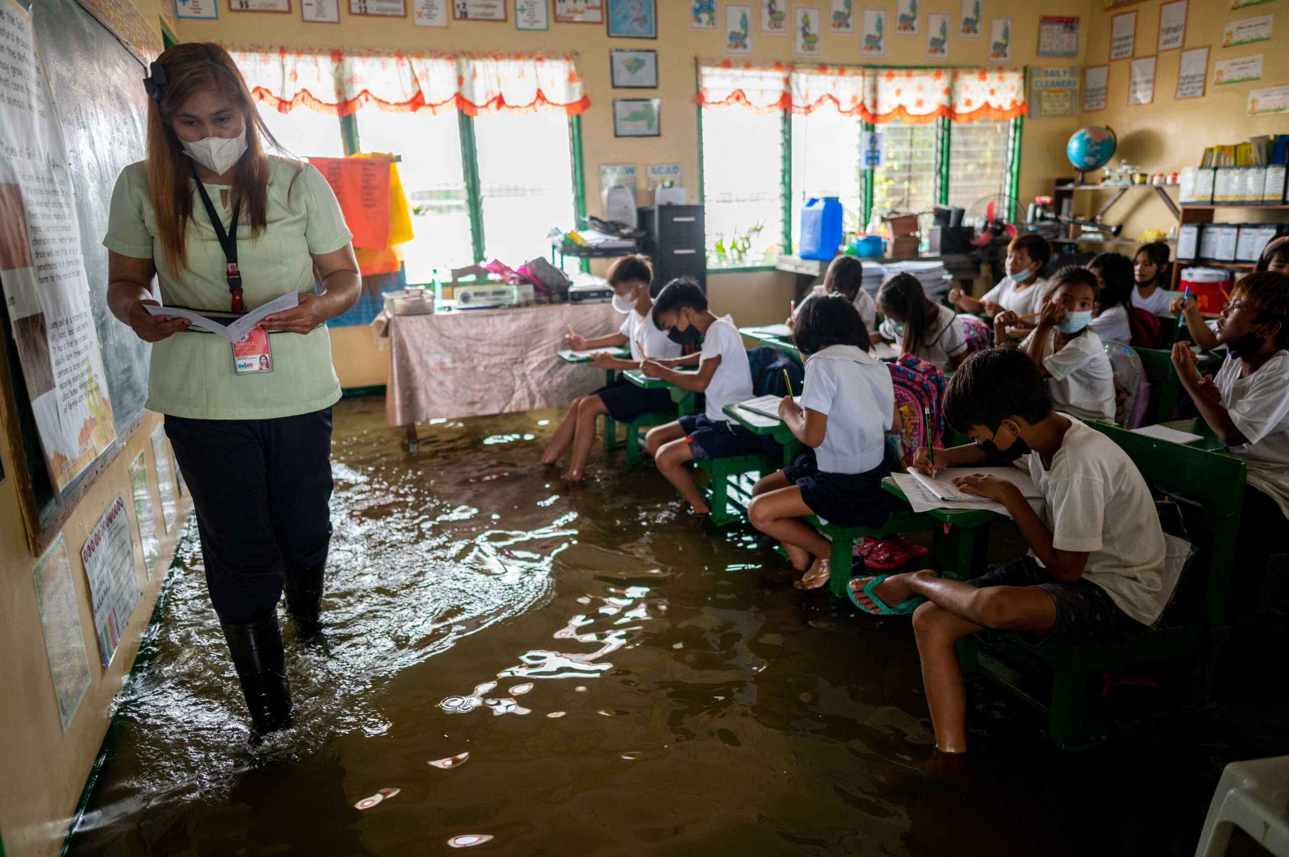Public school teacher Mylene Ambrocio leads the class during the first day of in-person classes, at a flooded school due to high tide, in Macabebe, Pampanga province, Philippines, August 22, 2022. REUTERS