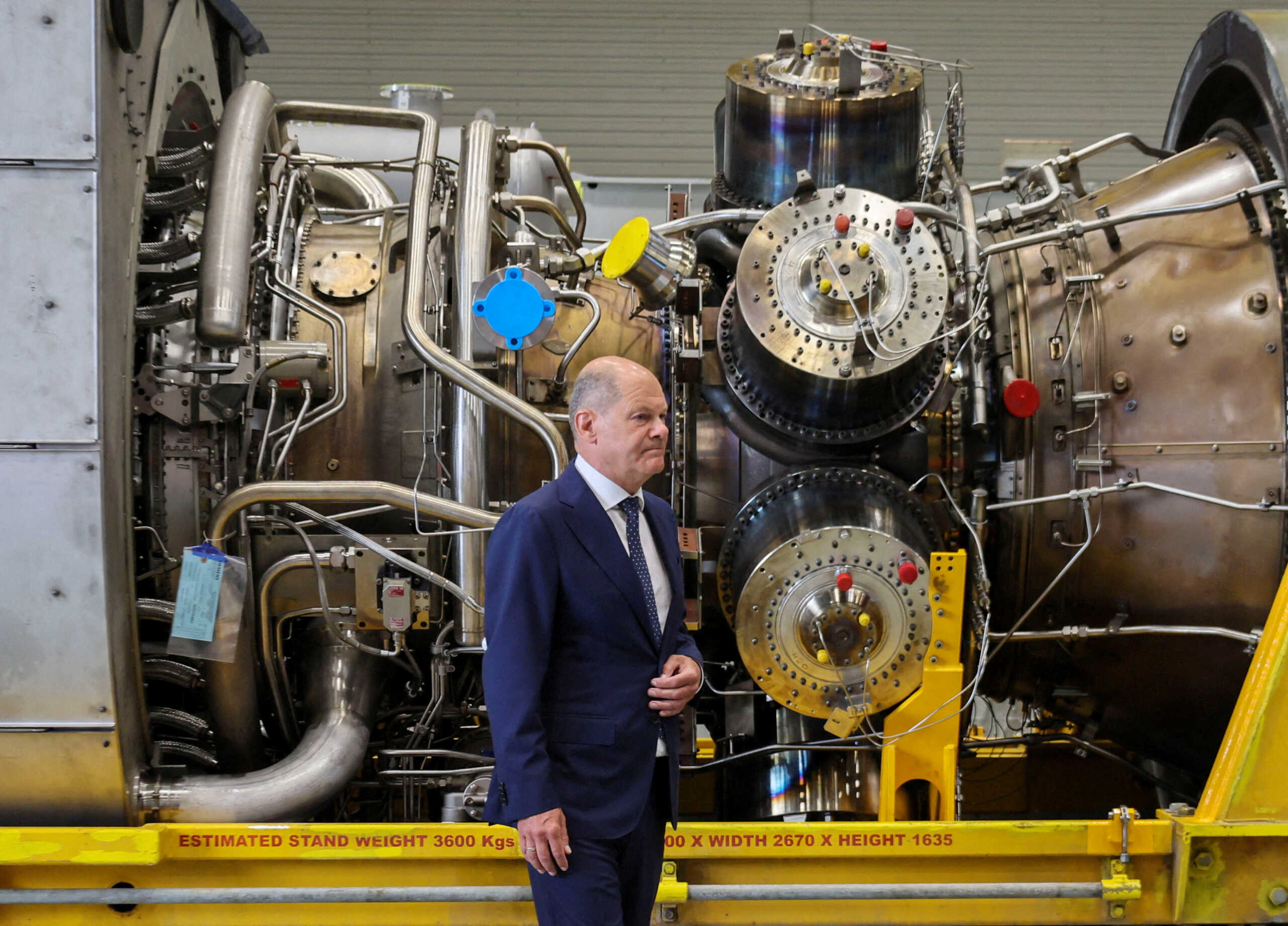German Chancellor OIaf Scholz stands next to a gas turbine meant to be transported to the compressor station of the Nord Stream 1 gas pipeline in Russia during his visit to Siemens Energy's site in Muelheim an der Ruhr, Germany, August 3, 2022. REUTERS