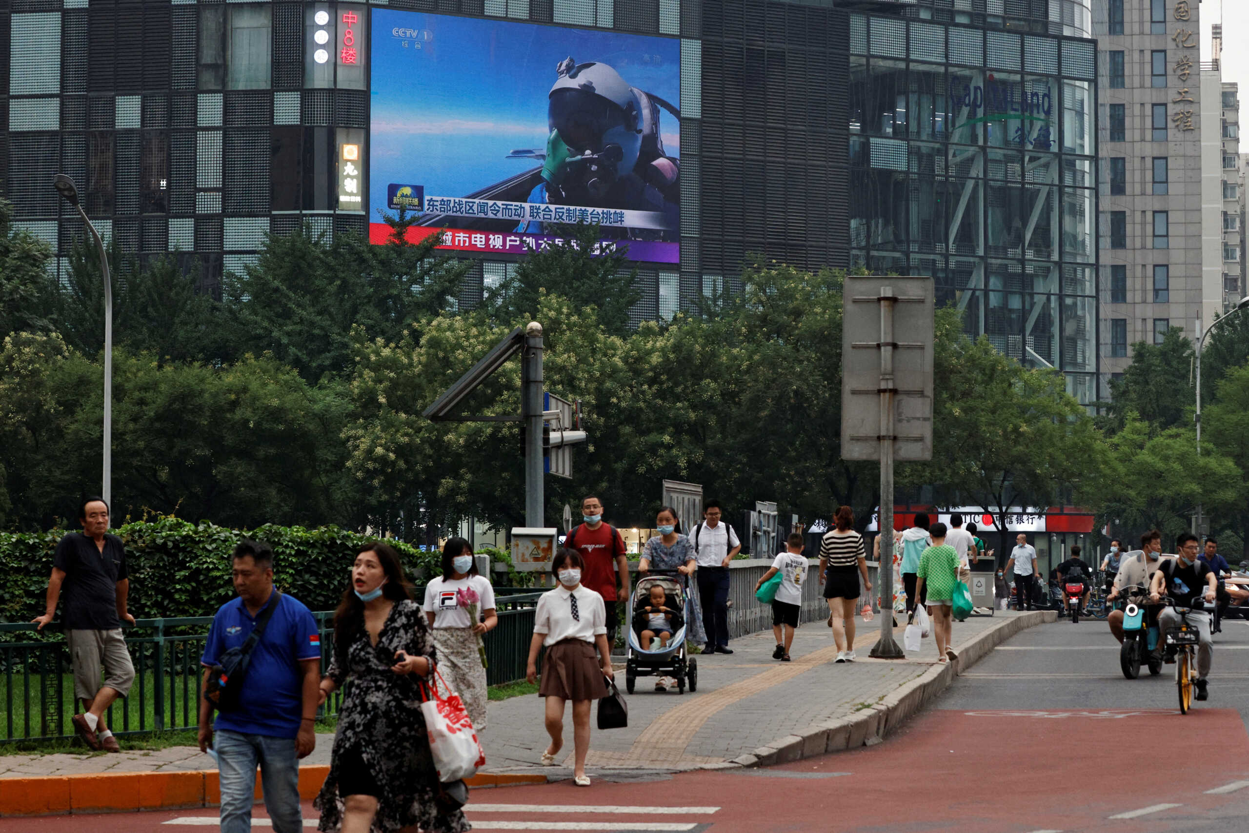 Pedestrians walk past a giant screen broadcasting news report on Chinese People's Liberation Army's (PLA) military exercises around Taiwan, in Beijing, China August 4, 2022. REUTERS