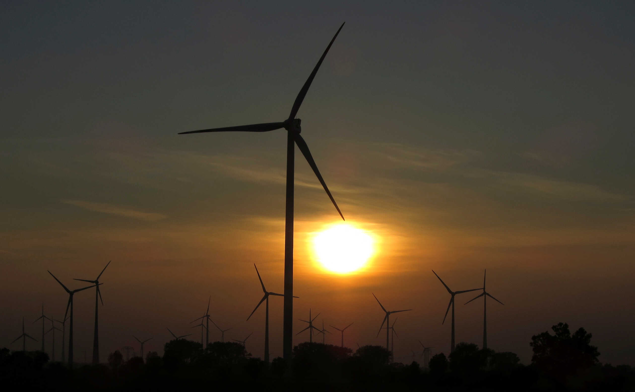 FILE PHOTO: The sun sets behind power-generating wind turbines from a wind farm near the village of Ludwigsburg, northern Germany October 5, 2014.   REUTERS