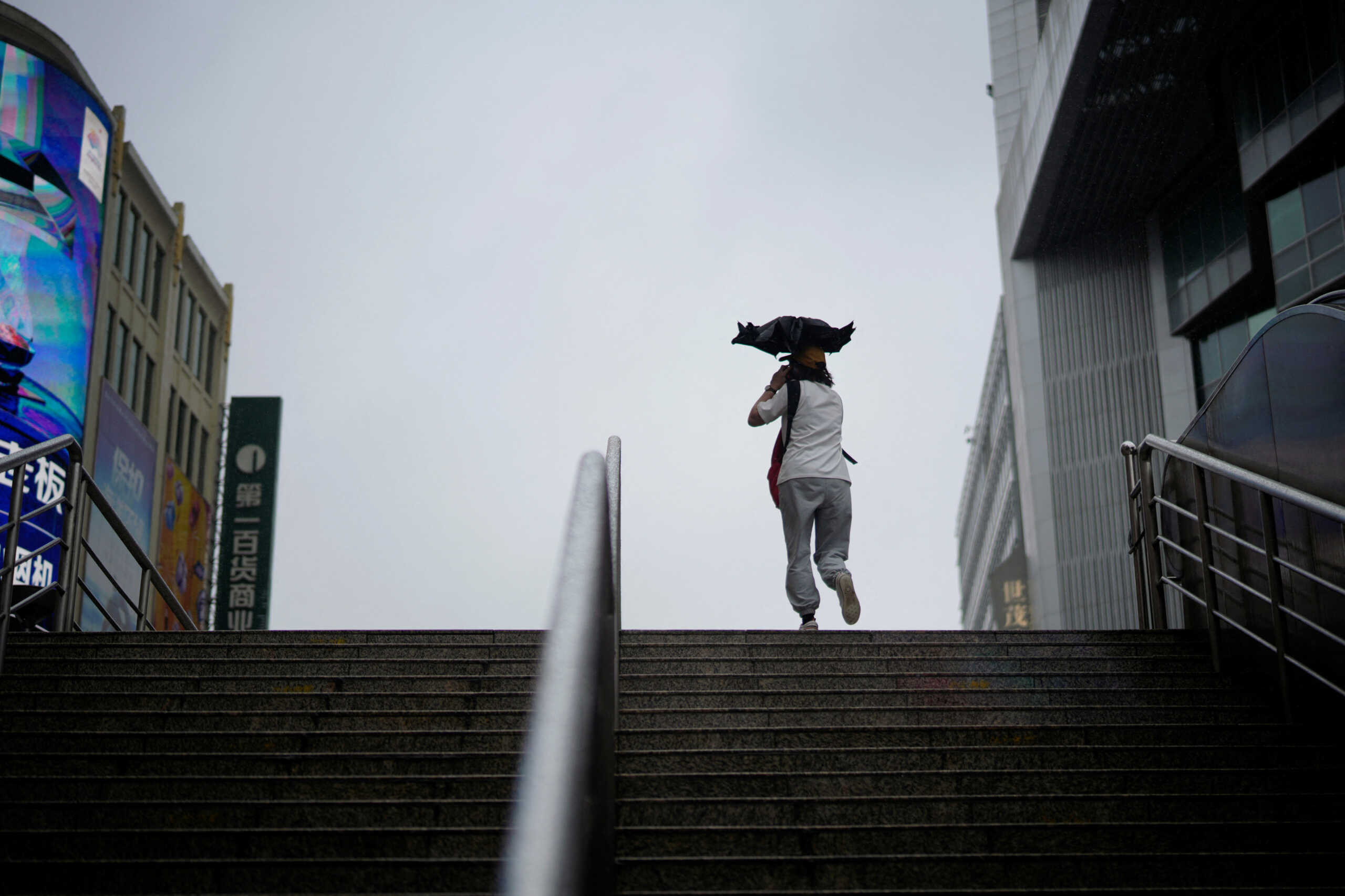 A pedestrian walks with an umbrella amid rain and wind brought by Typhoon Muifa, in Shanghai, China September 14, 2022. REUTERS