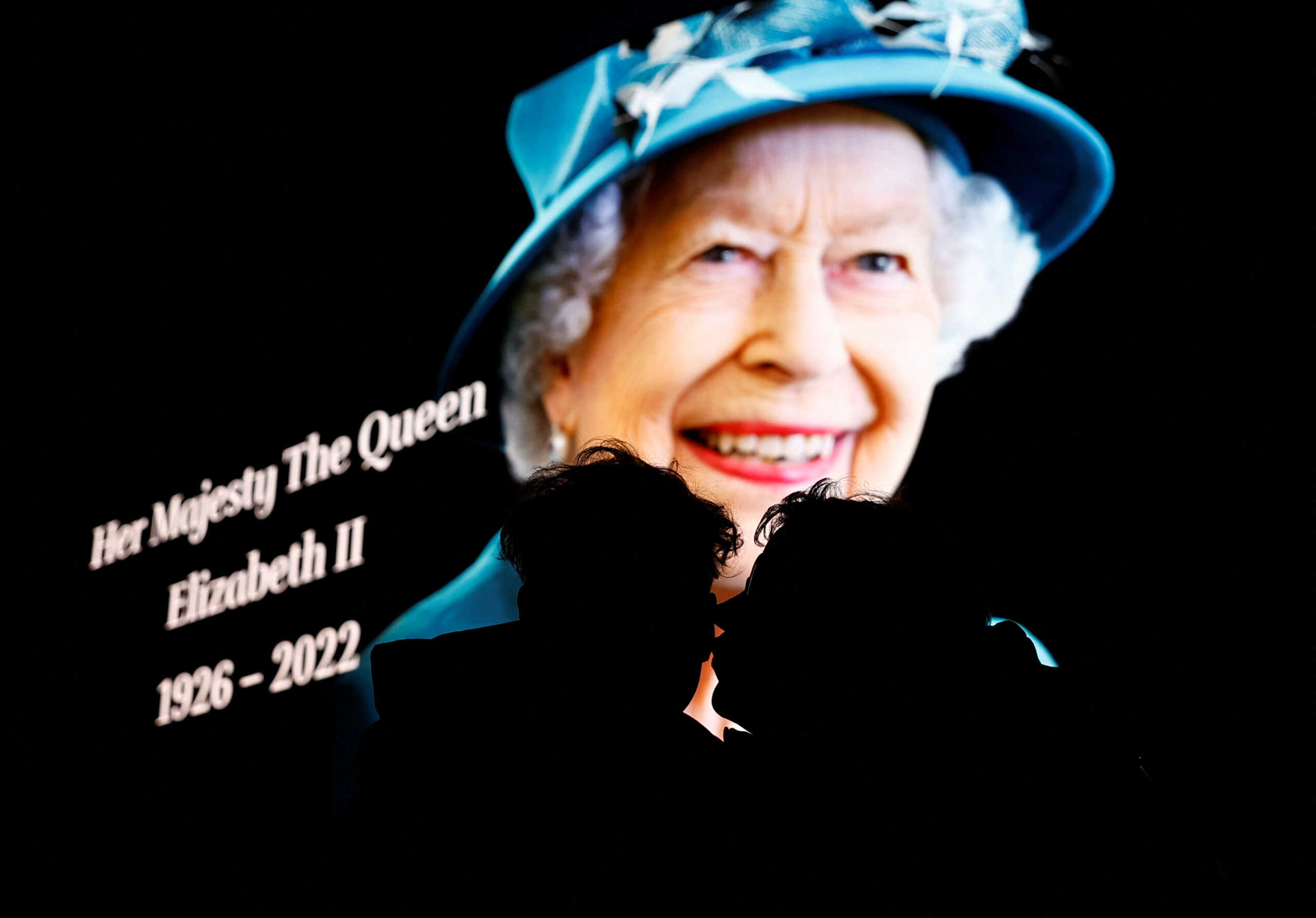 People embrace as an image of  Queen Elizabeth, Britain's longest-reigning monarch and the nation's figurehead for seven decades is displayed at Piccadilly Circus after she died aged 96, according to Buckingham Palace, in London, Britain September 8, 2022. REUTERS