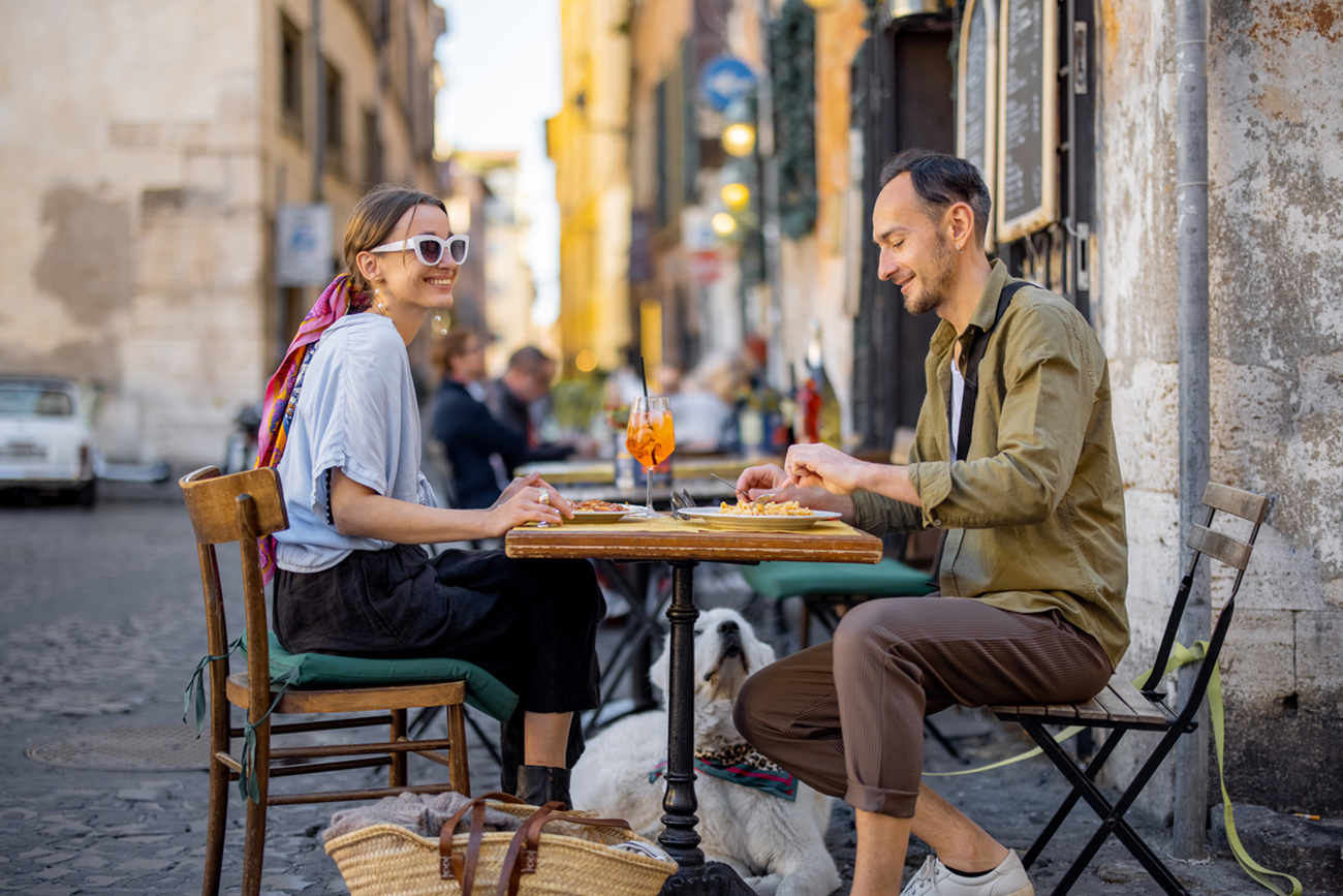 Man and woman eating italian pasta and drinking wine at restaurant on the street in Rome. Concept of Italian gastronomy and travel. Italian couple having lunch together