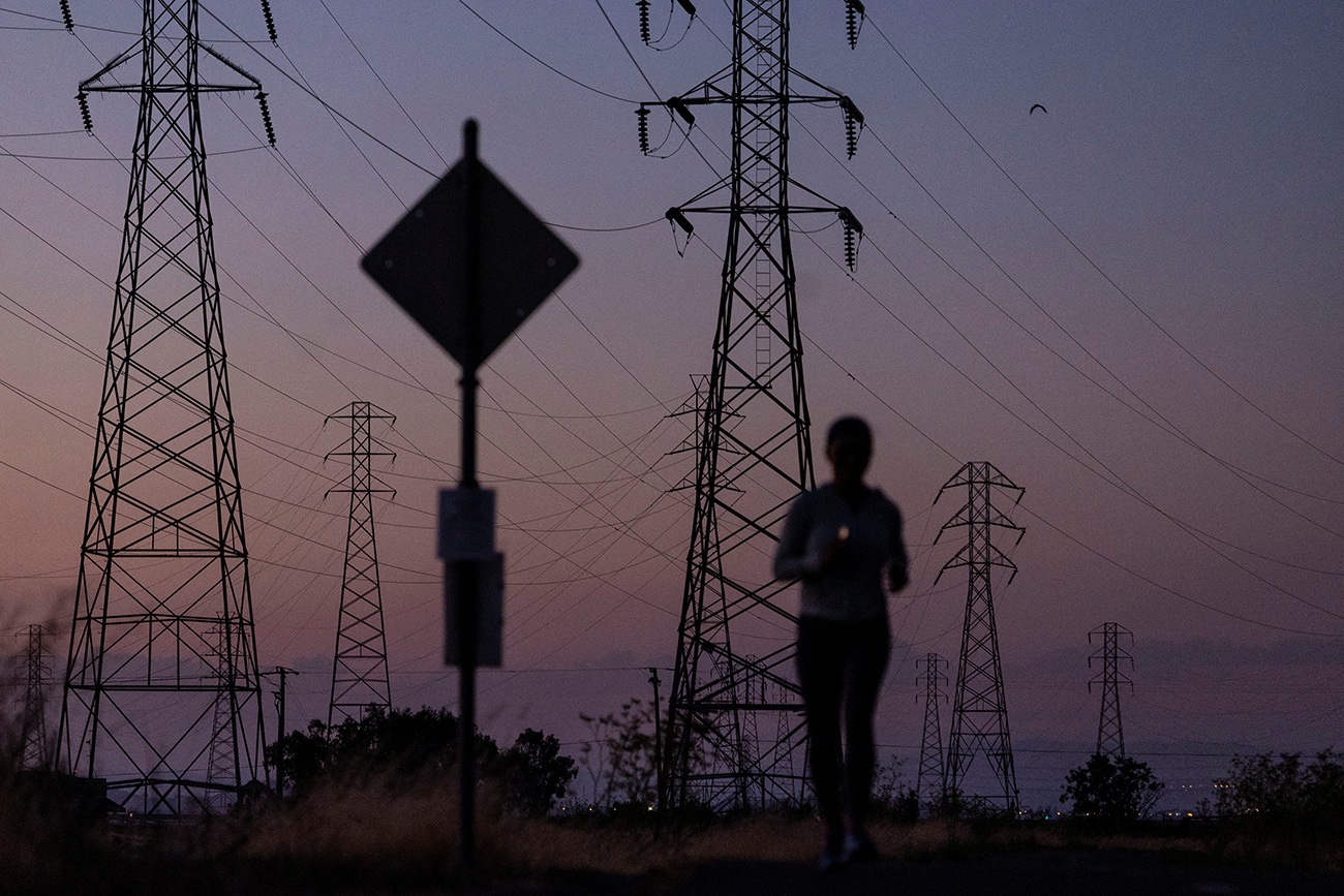 A woman jogs by power lines, as California's grid operator urged the state's 40 million people to ratchet down the use of electricity in homes and businesses as a wave of extreme heat settled over much of the state, in Mountain View, California, U.S., August 17, 2022. REUTERS