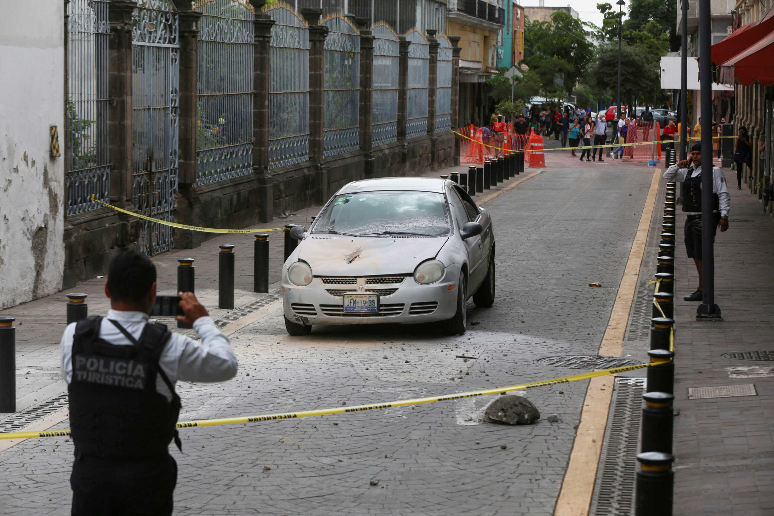 A police officer takes a picture of a car damaged by rocks that fell off a church during an earthquake, in Guadalajara, Mexico September 19, 2022. REUTERS