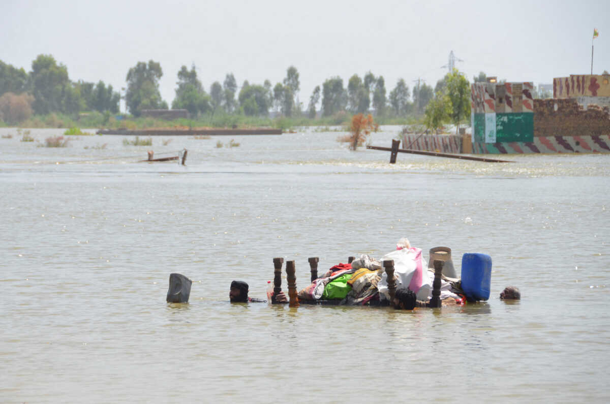 Three flood victims float their belongings on an upturned table, following rains and floods during the monsoon season in Dera Allah Yar, Jafferabad District, Pakistan, September 5, 2022. REUTERS